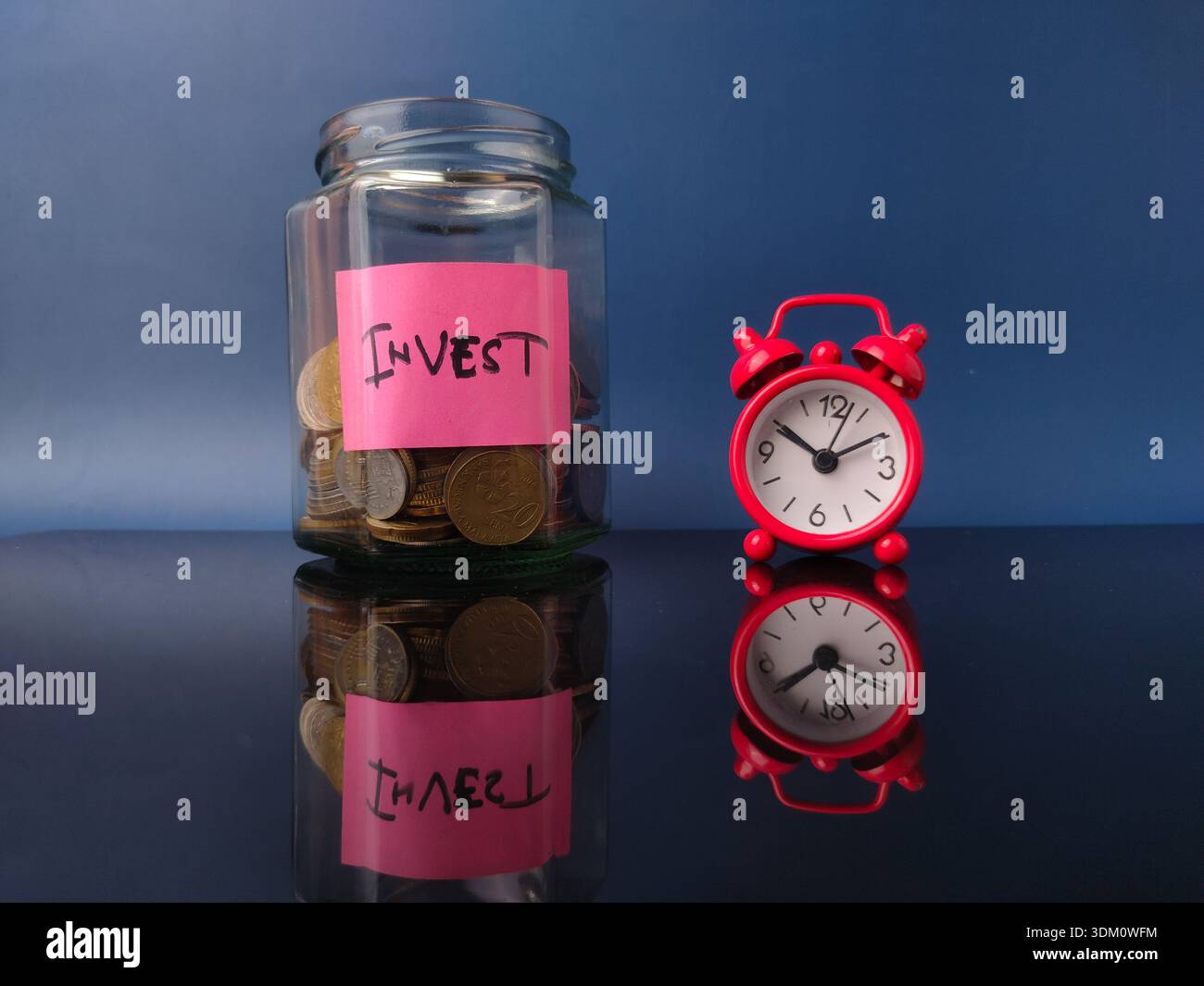 La sveglia rossa accanto ad essa rappresenta il passare del tempo e l'urgenza di iniziare a investire. Foto Stock