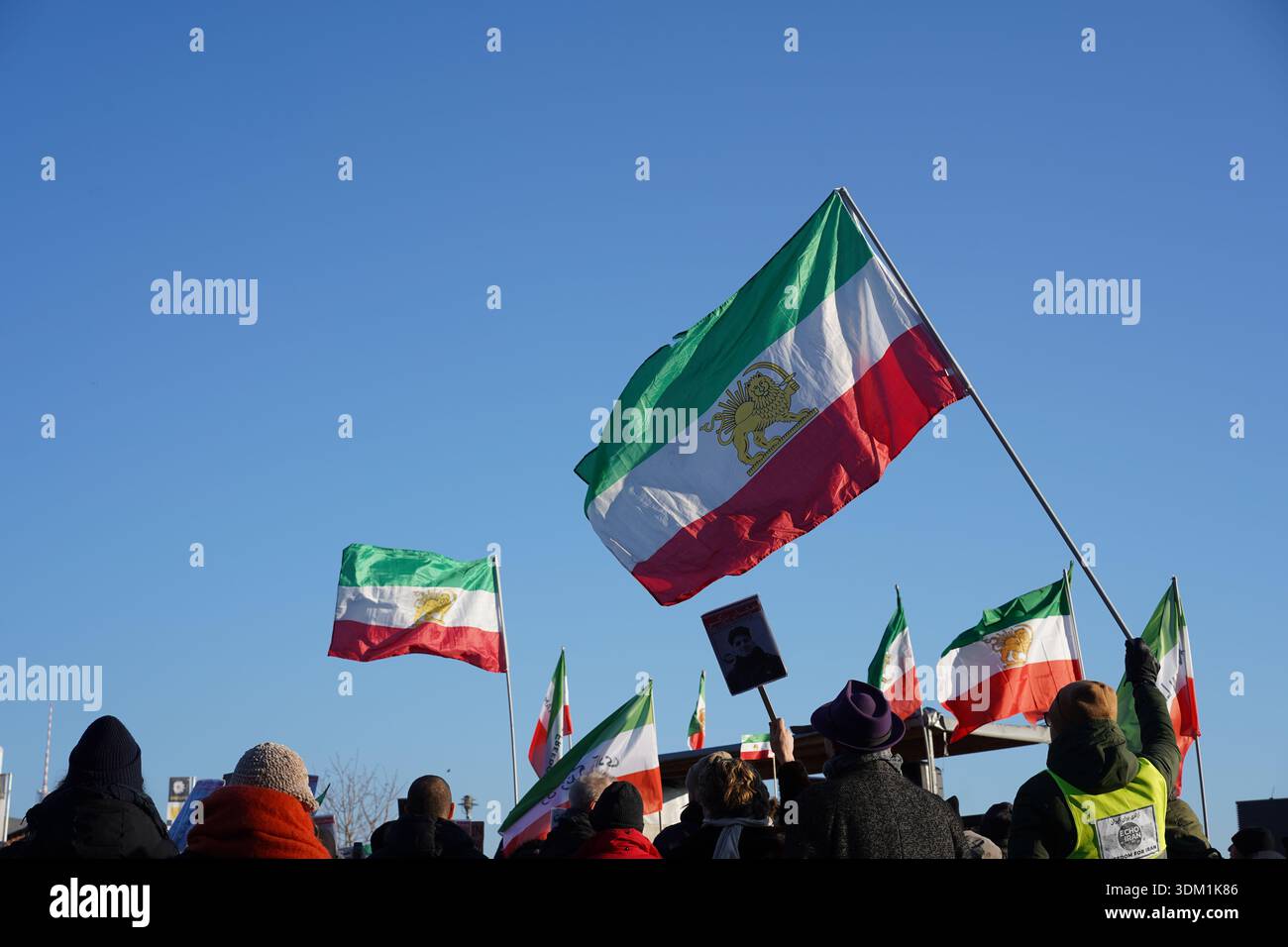 Berlino, Germania - 18 gennaio 2026: I manifestanti ondeggiano le bandiere iraniane del Leone e del Sole a Echo Iran, manifestazione contro il regime a Washingtonplatz, Berlino Foto Stock