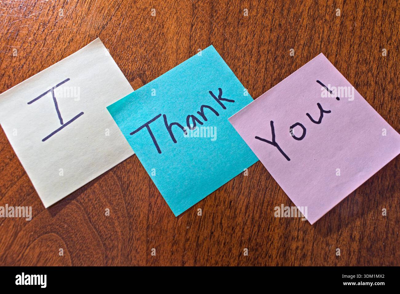 Tre appunti con messaggi scritti a mano che scrivono i Thank you sono posizionati diagonalmente su un tavolo di legno testurizzato. Foto Stock