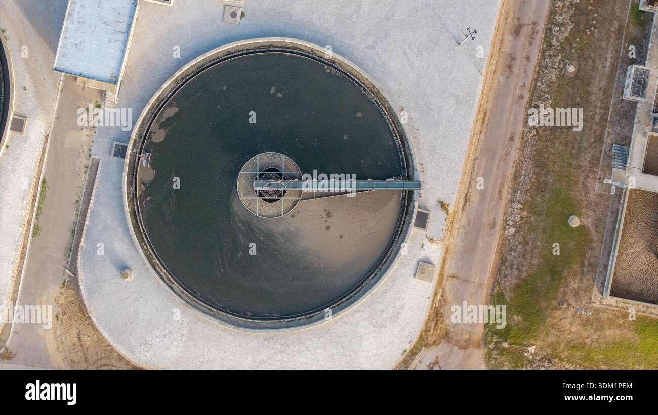 Veduta aerea di un impianto circolare di trattamento delle acque con le sue acque grigie in contrasto con la vegetazione circostante in cemento e in paracadute, Kraaifo Foto Stock