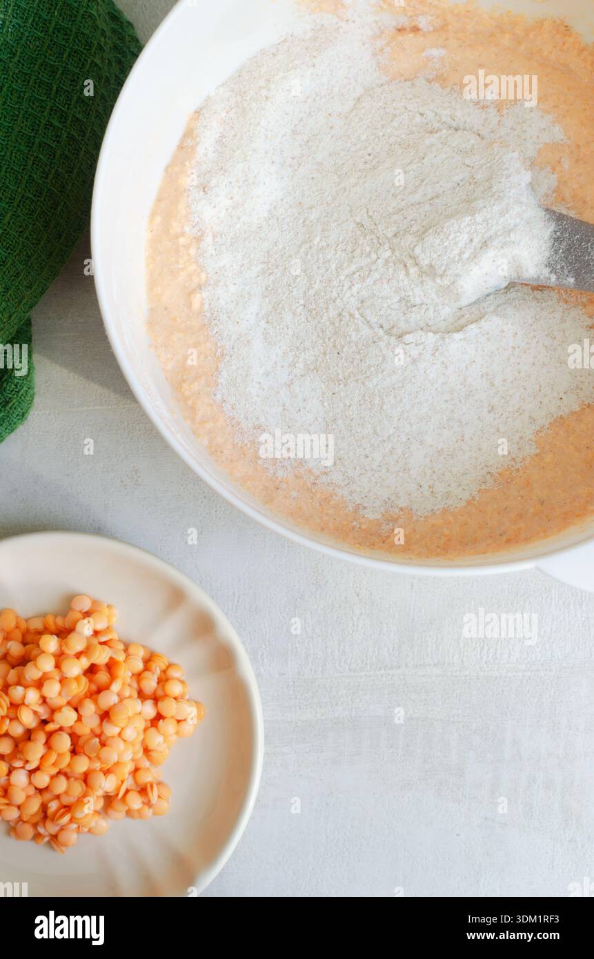Lenticchie con farina integrale in un recipiente bianco. Sano concetto di cottura vegan con texture naturali e sfondo minimale, temi alimentari sani. Superiore Foto Stock