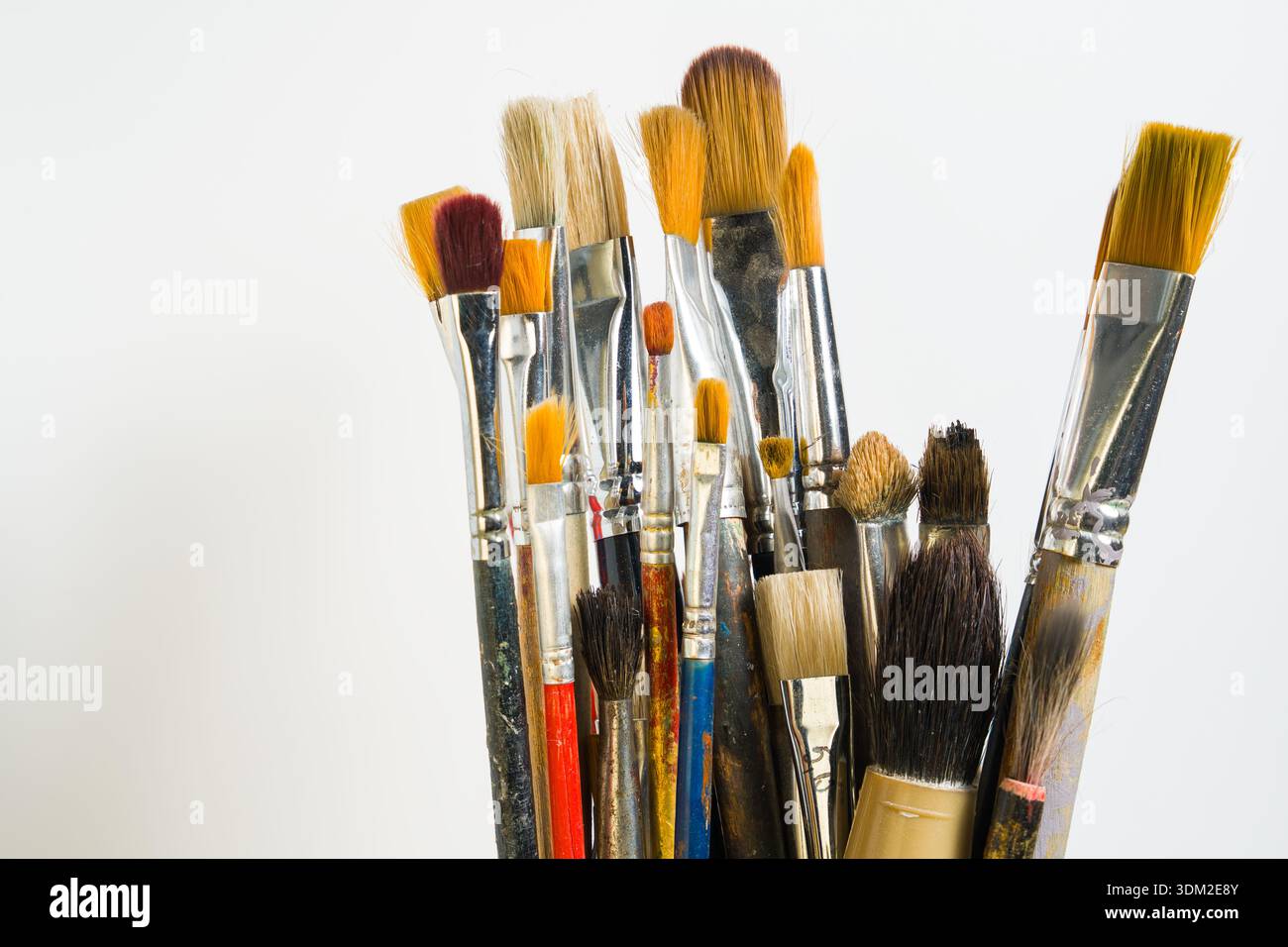 Una collezione di vari pennelli viene mostrata in posizione verticale su uno sfondo chiaro. Questi pennelli sono utilizzati per la pittura e per scopi artistici. Foto Stock