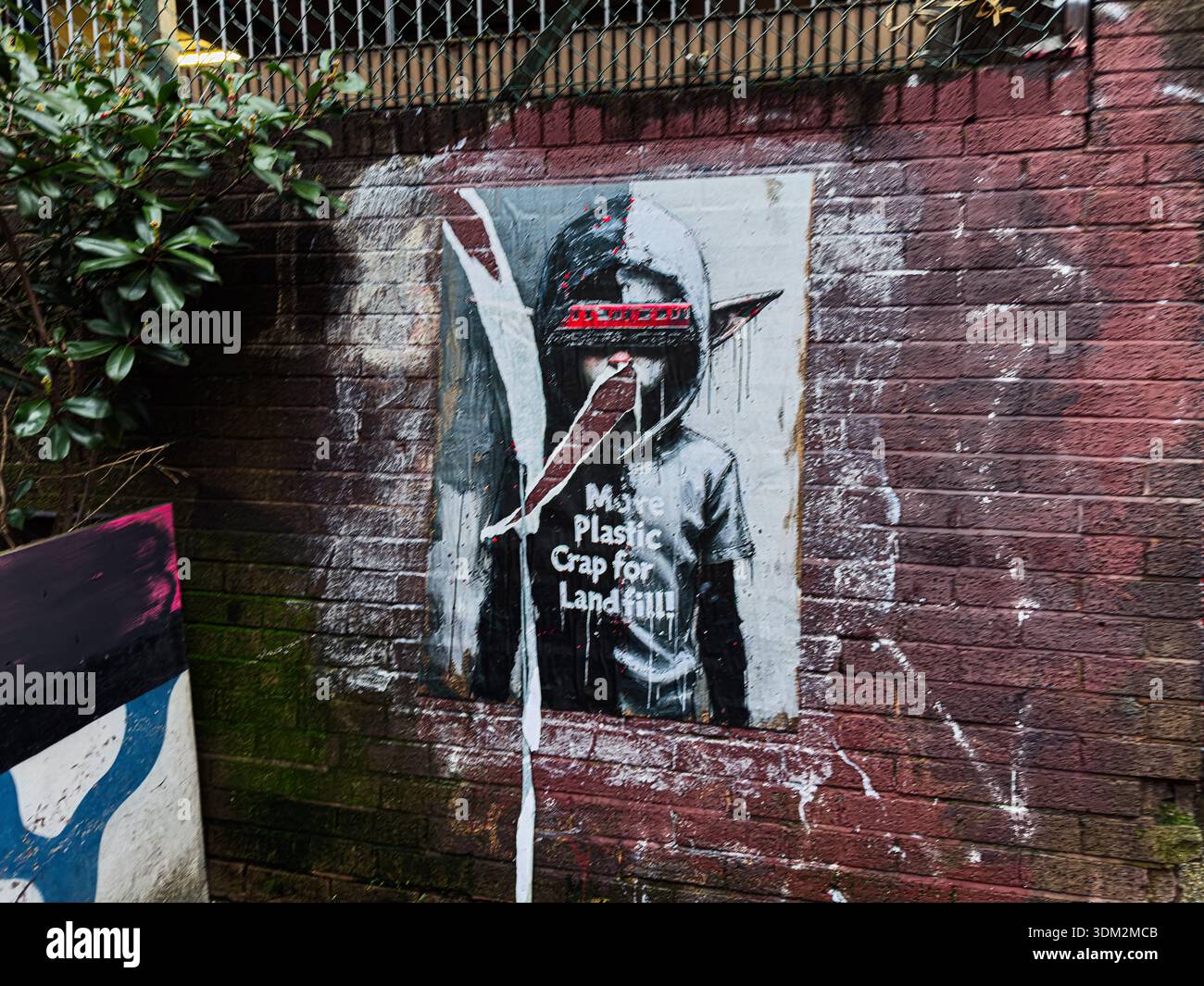 Manchester, Regno Unito - 21 gennaio 2026: Murale a figura con cappuccio a Manchester con messaggio di protesta su discariche e rifiuti. Foto Stock