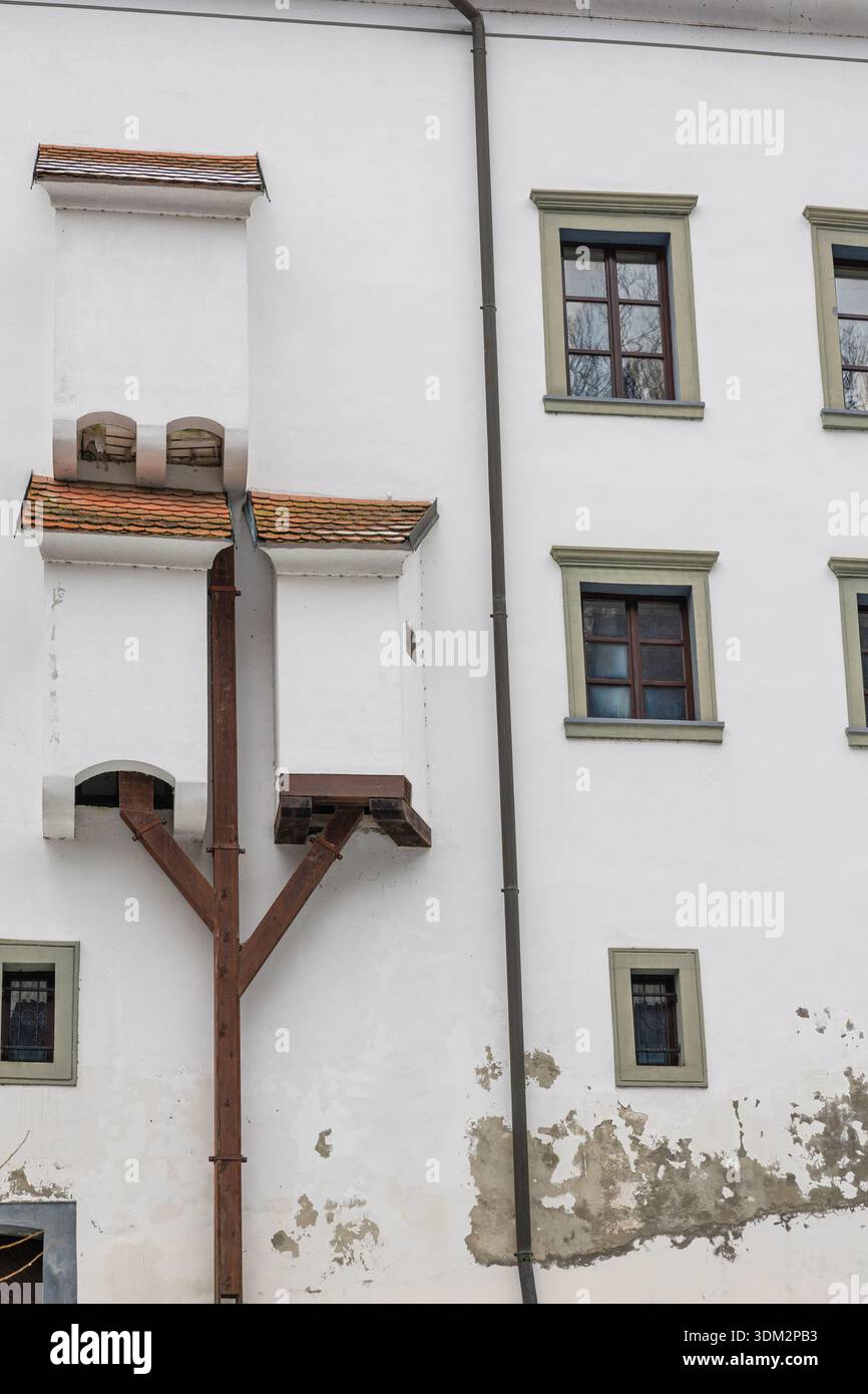 La facciata di un edificio in gesso bianco presenta piccoli tetti piastrellati, finestre multiple e servizi igienici del castello Foto Stock