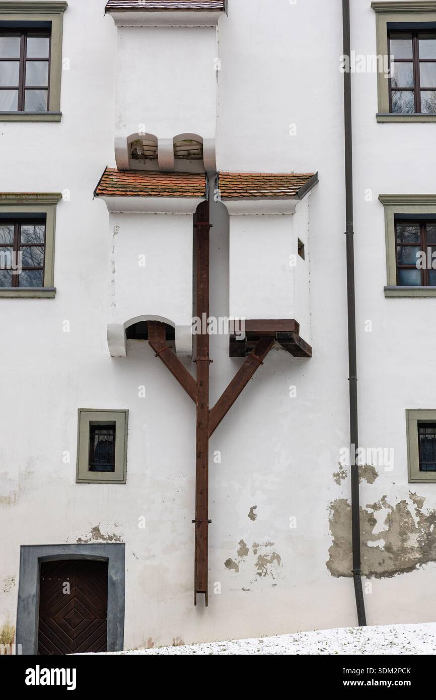 La facciata di un edificio in gesso bianco presenta piccoli tetti piastrellati, finestre multiple e servizi igienici del castello Foto Stock