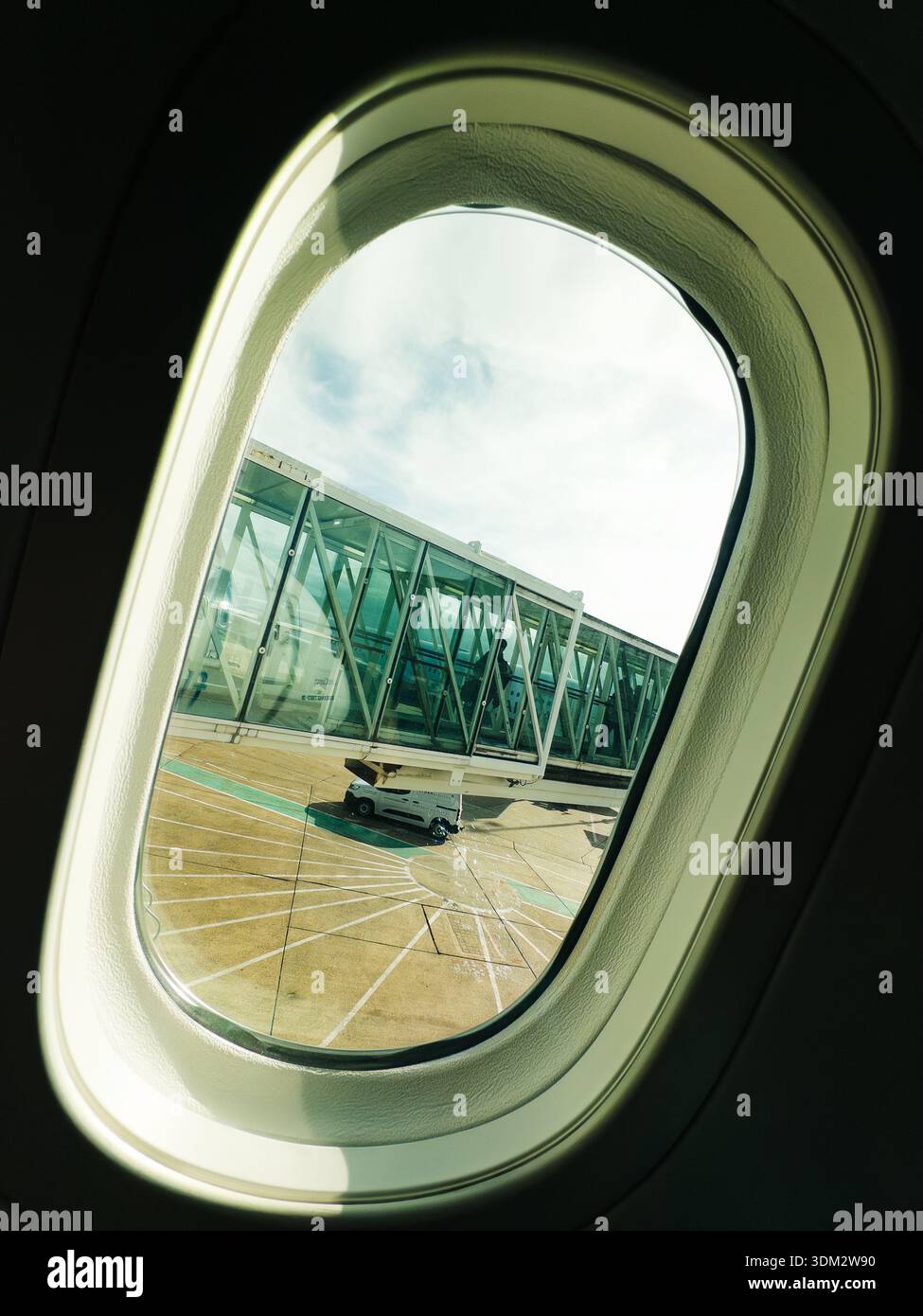 Vista dall'alto del ponte jet in vetro collegato agli aerei sul piazzale dell'aeroporto sotto i cieli soleggiati con nuvole - Immagine stock catturata con smartphone