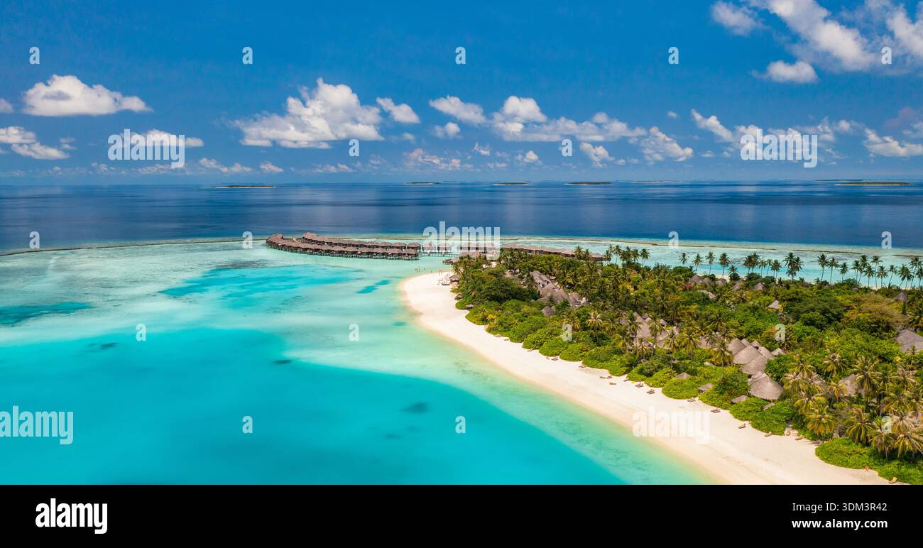 Vista aerea del lussureggiante resort tropicale dell'isola circondato da un oceano turchese mozzafiato delle Maldive, una destinazione paradisiaca esotica da sogno, un luminoso drone Foto Stock