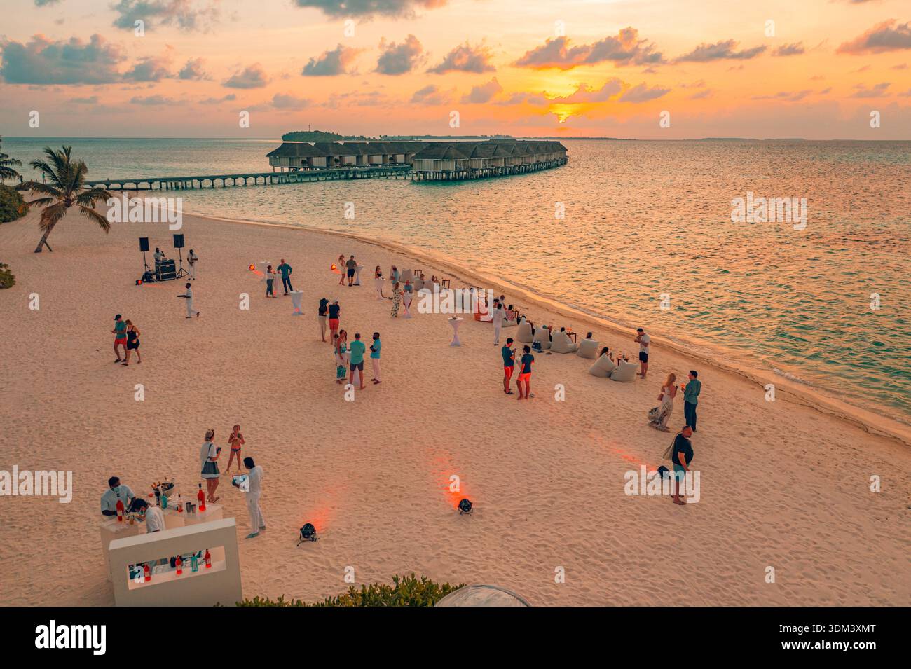 Vista aerea della festa in spiaggia delle Maldive al tramonto, resort con ville sull'acqua, spiaggia sabbiosa, scenario di vacanza tropicale Foto Stock