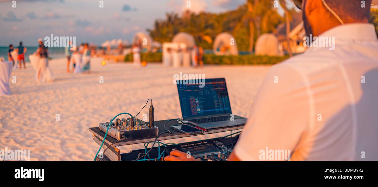 DJ che suona musica festa in spiaggia atmosfera al tramonto vita notturna tropicale balli della folla celebrazione del mare destinazione di viaggio Foto Stock