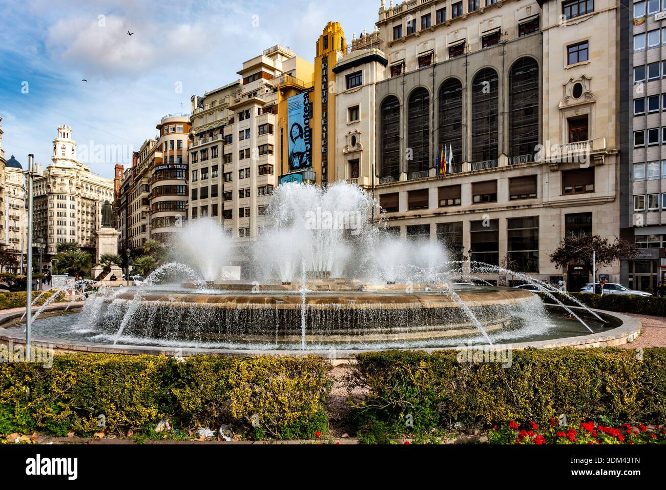 La fontana circolare in Plaza del Ayuntamiento spruzza l'acqua sullo sfondo di iconici edifici Art Deco come il Teatro Rialto. Foto Stock