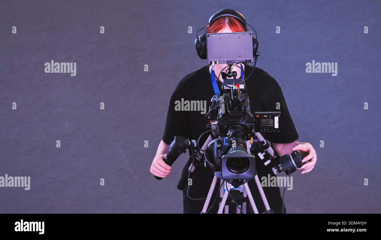 Professionista della produzione multimediale che utilizza una videocamera per la trasmissione o le riprese Foto Stock