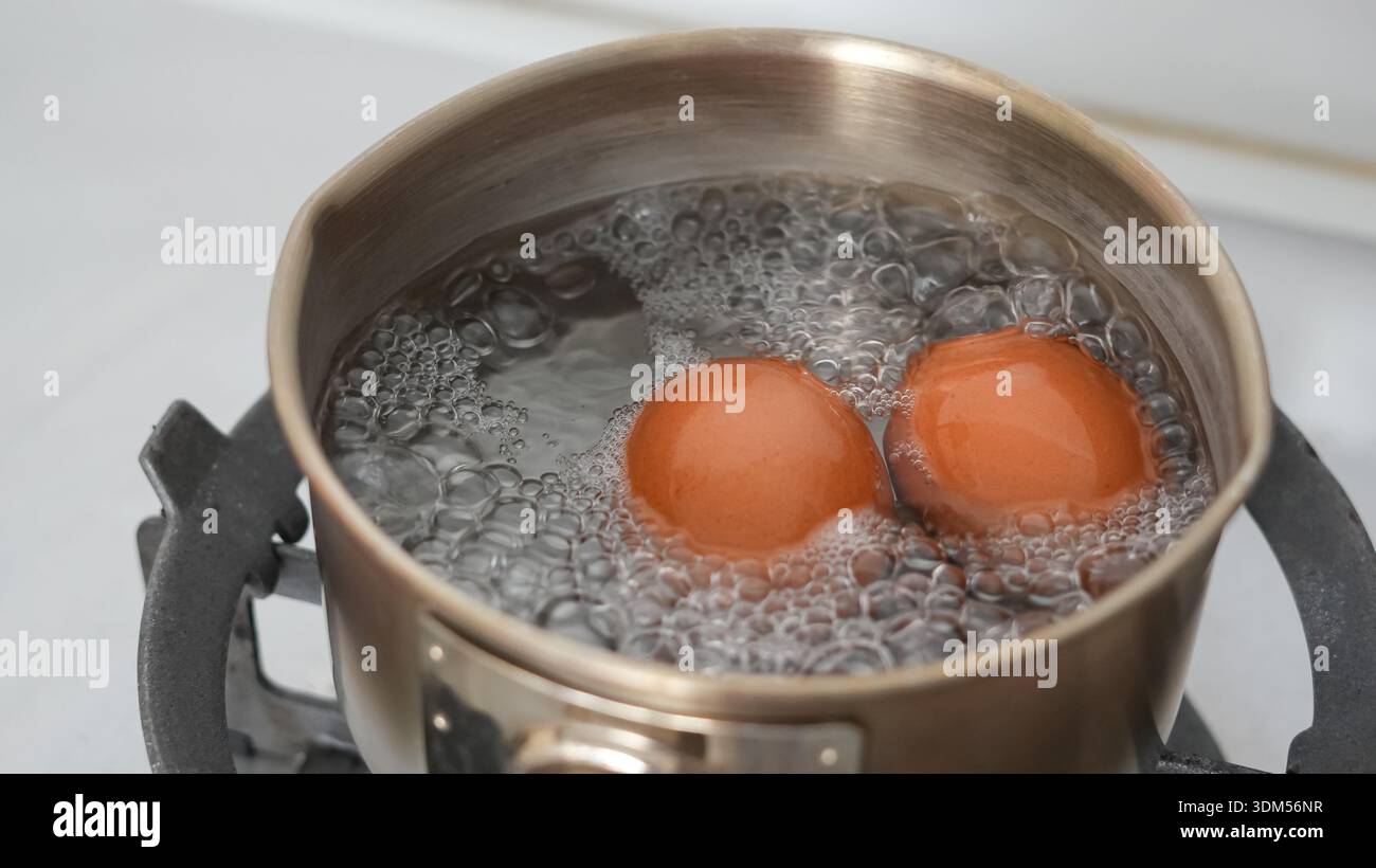 Uova bollenti con pentola in acciaio inossidabile per colazione Foto Stock