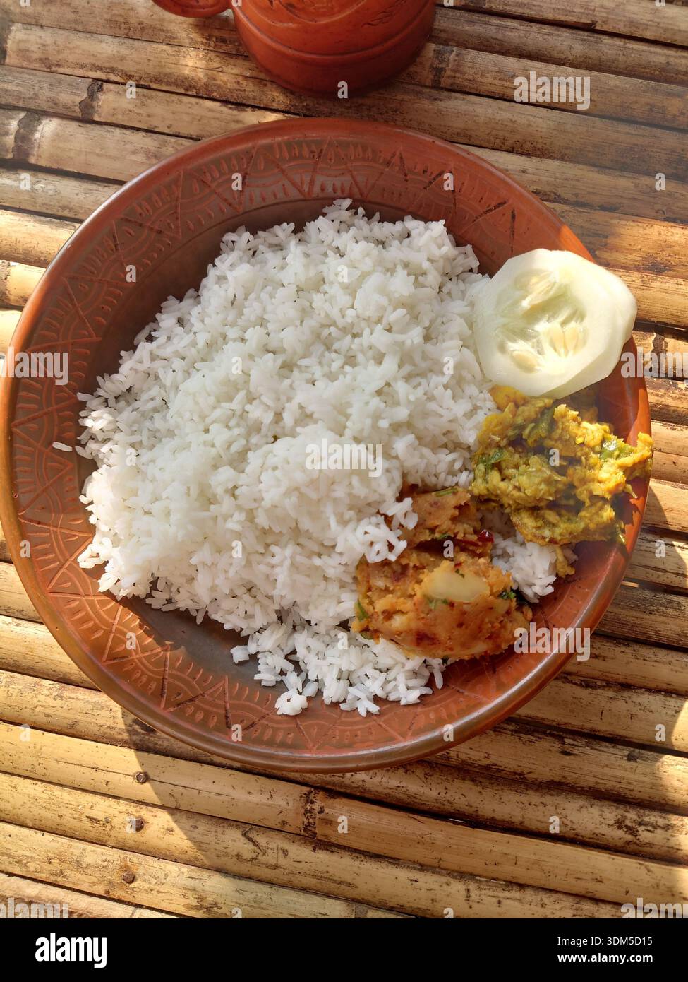 Tradizionale pasto bengalese con riso, curry e verdure servito su un tavolo di bambù nel Bangladesh rurale. Foto Stock