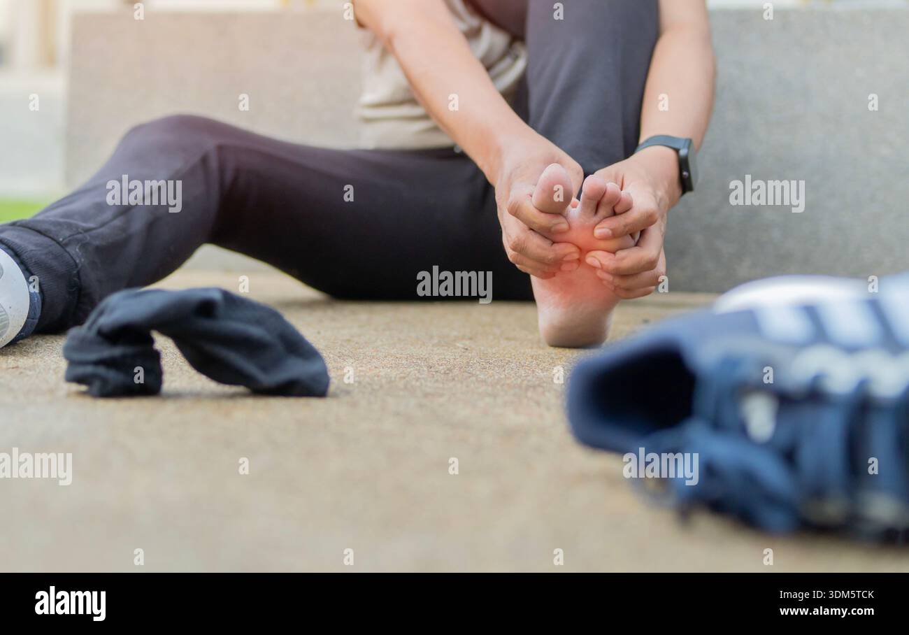 Un corridore sportivo che soffre di dolore al piede danneggiato, sente dolore ai crampi muscolari ferita al trauma sportivo infortunio alle gambe in allenamento all'aperto. Foto Stock