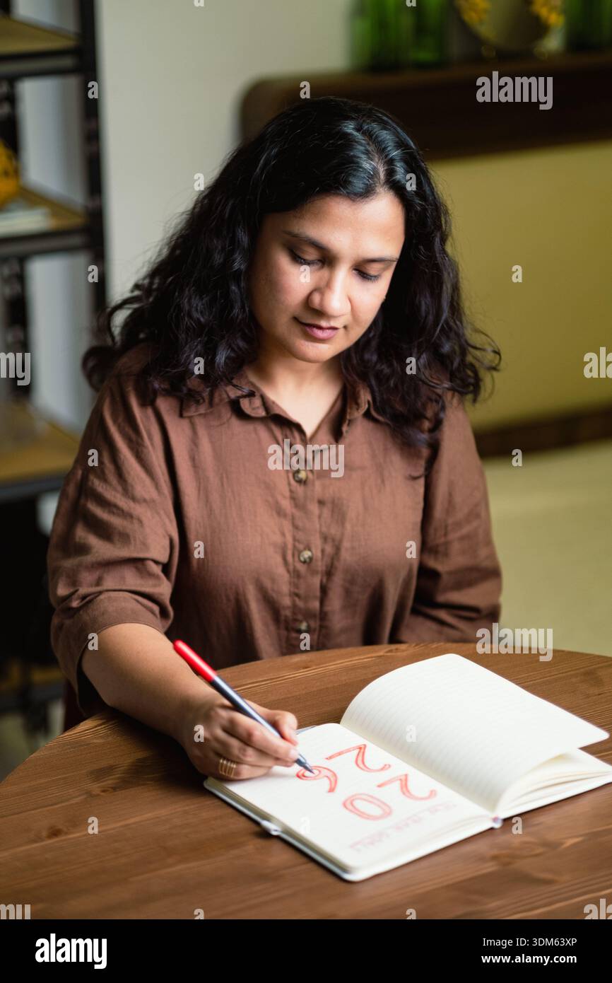 Donna che scrive su diario a casa cura di sé e concetto di definizione degli obiettivi Foto Stock