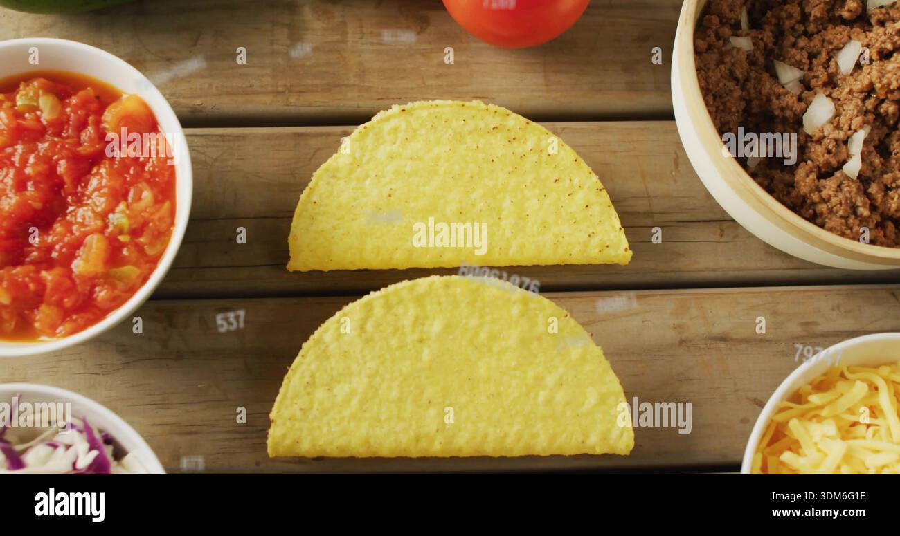 Due conchiglie gialle di taco di mais duro su un tavolo rustico, con salsa, manzo, formaggio, cavolo Foto Stock