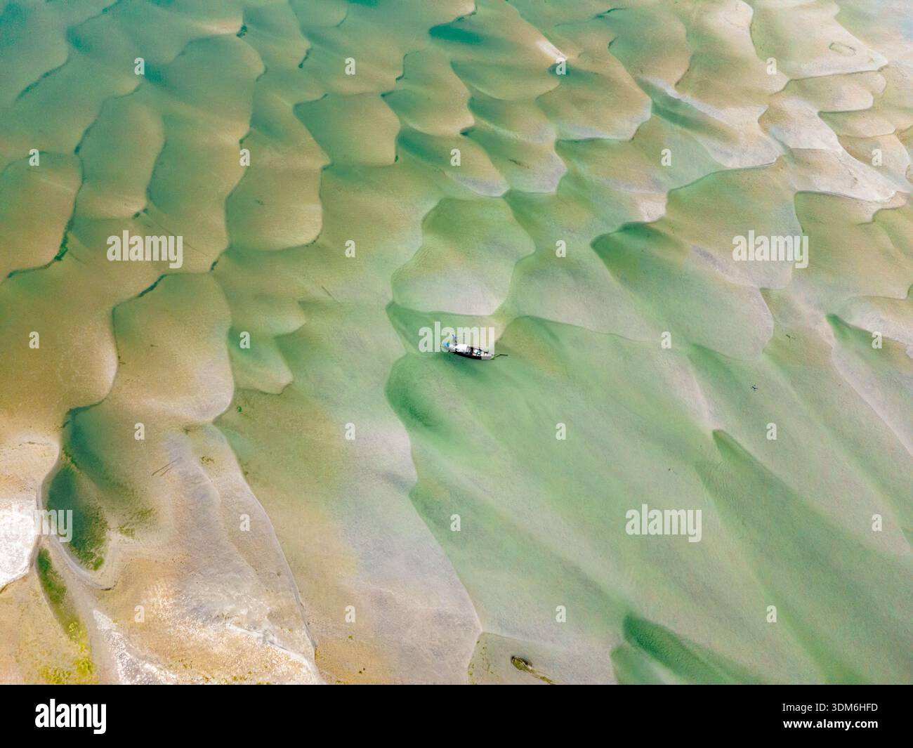 Rajbari, Bangladesh - 22 febbraio 2025: Veduta aerea di una barca solitaria che naviga sulle acque scintillanti e poco profonde, lasciando una delicata ondulazione attraverso la tex Foto Stock