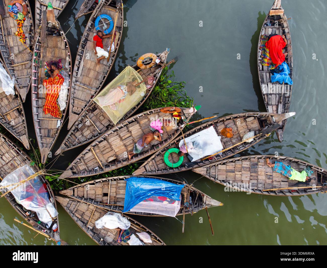 Dhaka, Bangladesh - 10 settembre 2024: Vista aerea delle barche raggruppate insieme, le loro logiche tessuti in legno contrastano con i tessuti vivaci e la S Foto Stock