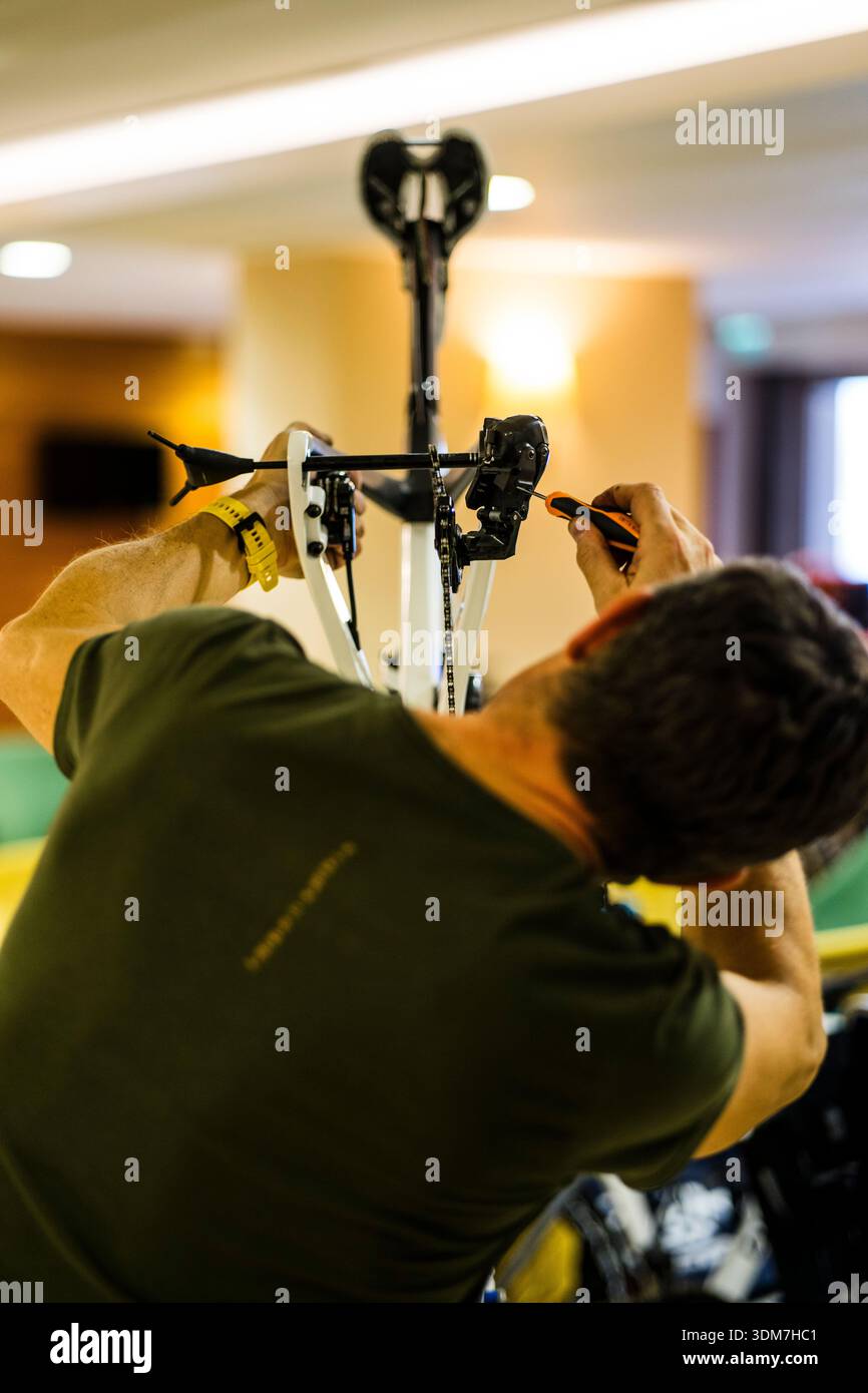 Vista posteriore ravvicinata di un meccanico professionista di biciclette, regolando con attenzione il deragliatore posteriore di una bici da strada bianca con un cacciavite. Foto Stock