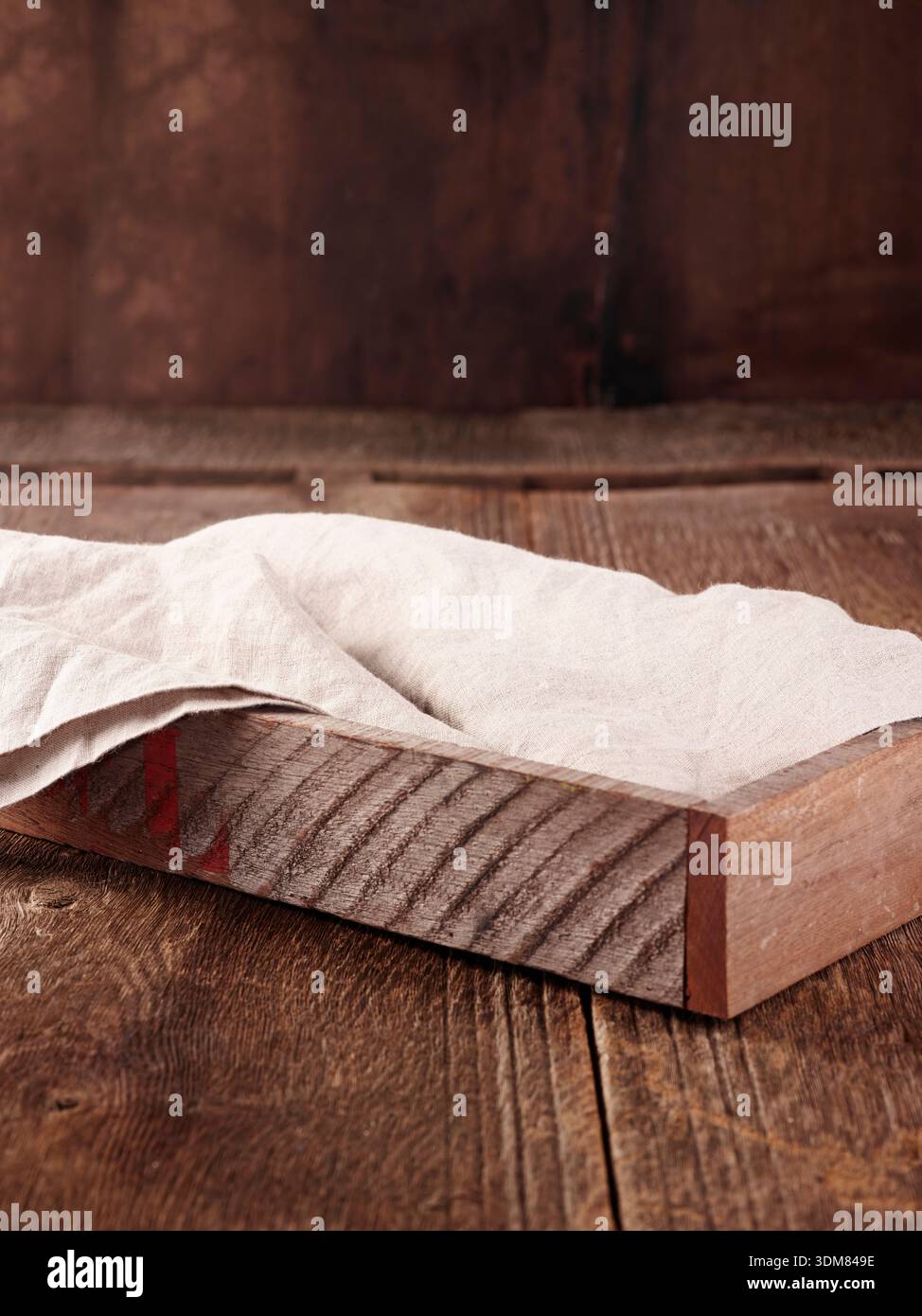Vassoio di legno rustico con tovagliolo di lino bianco drappeggiato su legno stagionato. Foto Stock
