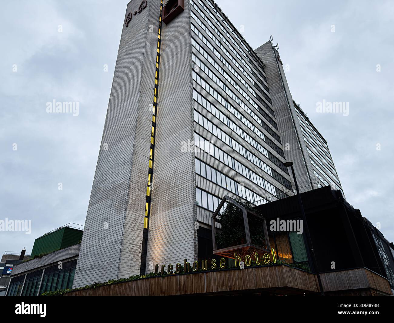 Manchester, Regno Unito - 21 gennaio 2026: Tall Treehouse Hotel a Manchester con finestre di vetro e un cartello al neon Treehouse hotel all'ingresso. Foto Stock