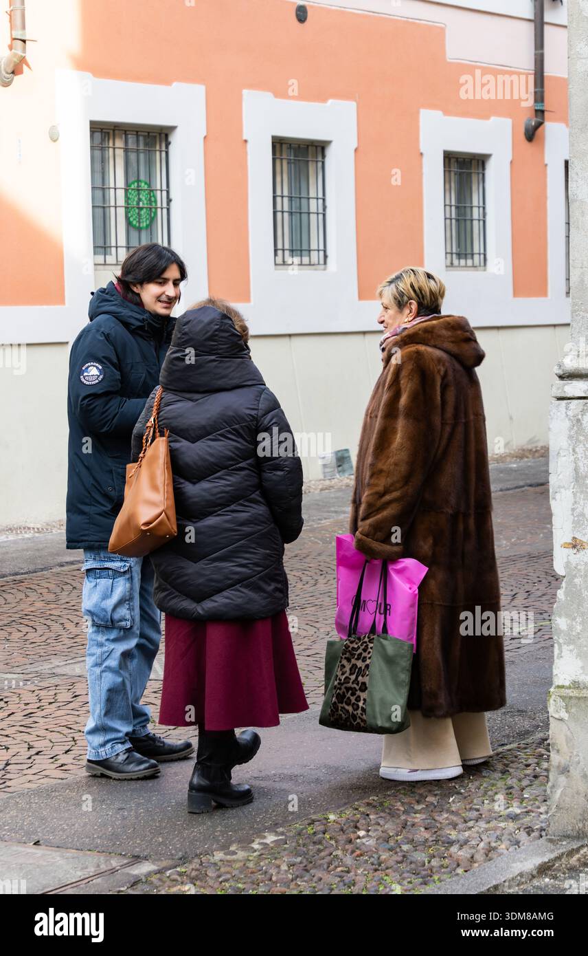 Gruppo di persone che si incontrano all'aperto indossando cappotti invernali sorridendo e parlando sulla strada della città durante la giornata fredda. Foto Stock