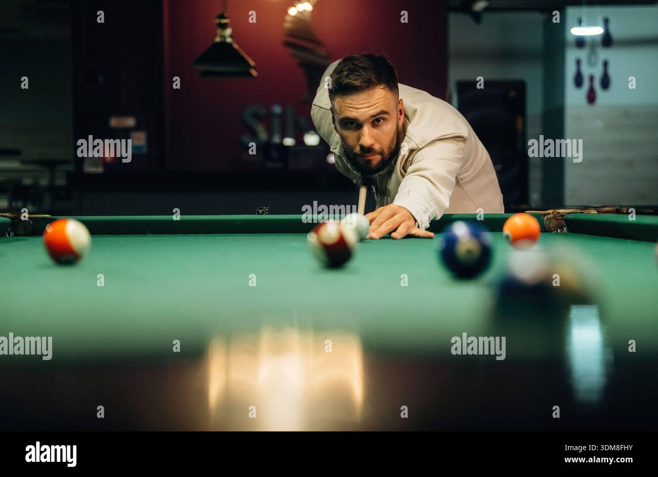 Usando una stecca. Bell'uomo con un gioco da biliardo. Foto Stock