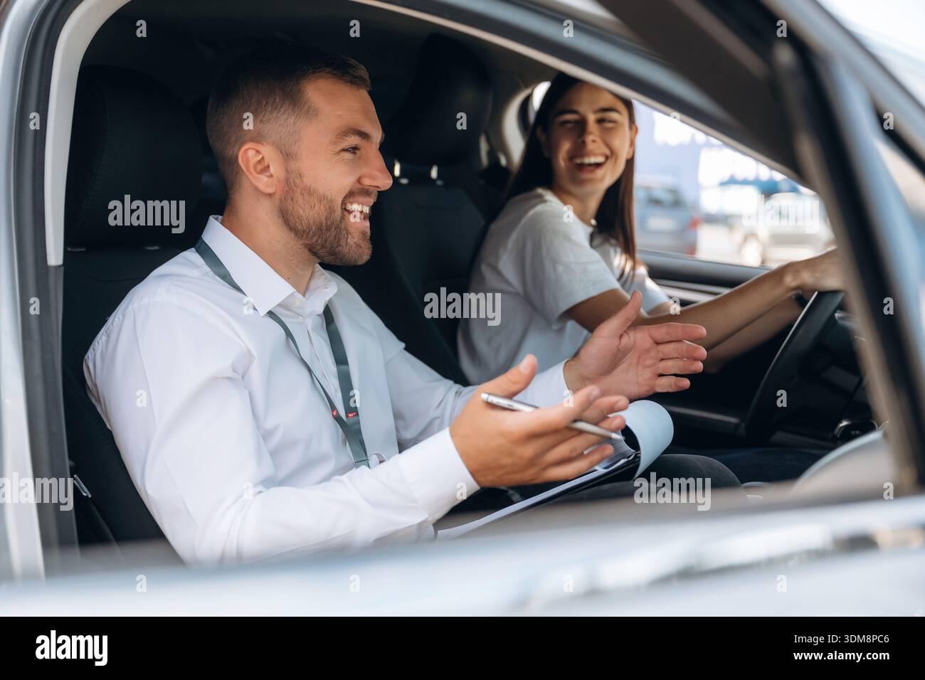 Umore positivo, sorridente. La donna e' con istruttore in macchina, concetto di scuola guida. Foto Stock