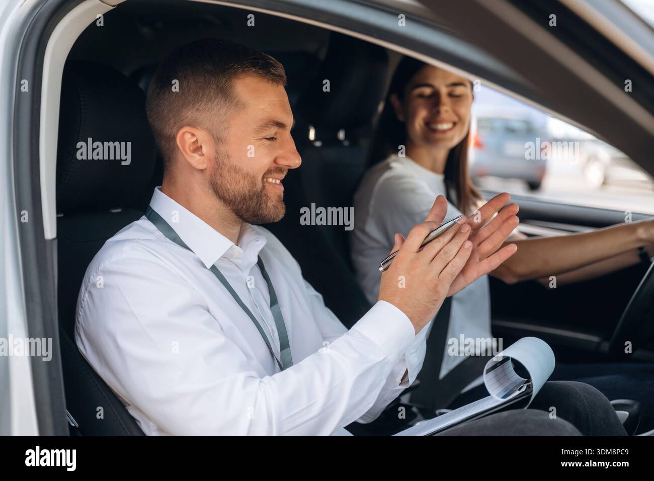 Umore positivo, sorridente. La donna e' con istruttore in macchina, concetto di scuola guida. Foto Stock