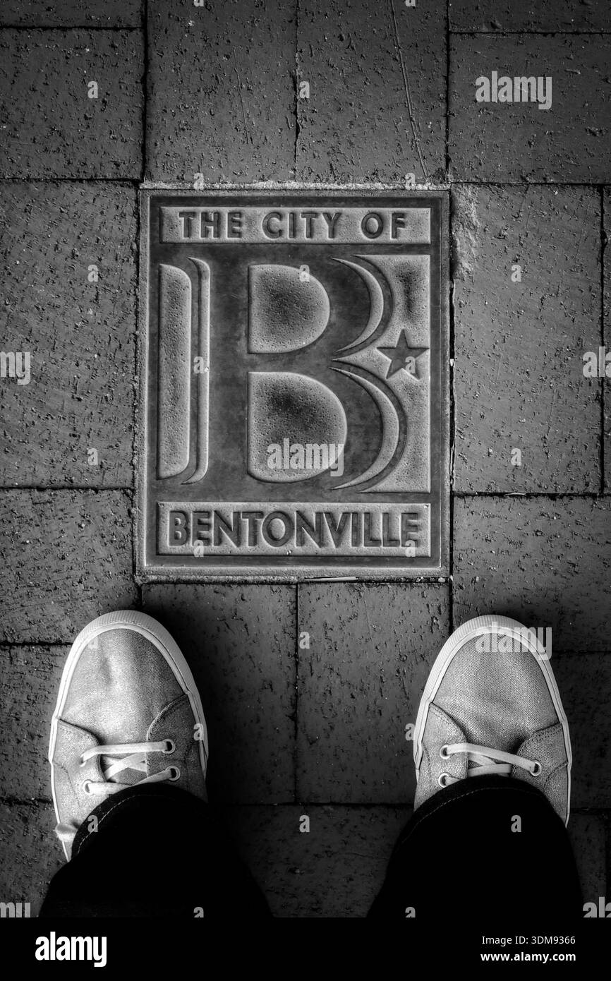 Placca decorativa sul marciapiede della città di Bentonville adagiata su un passaggio in mattoni rossi in bianco e nero Foto Stock