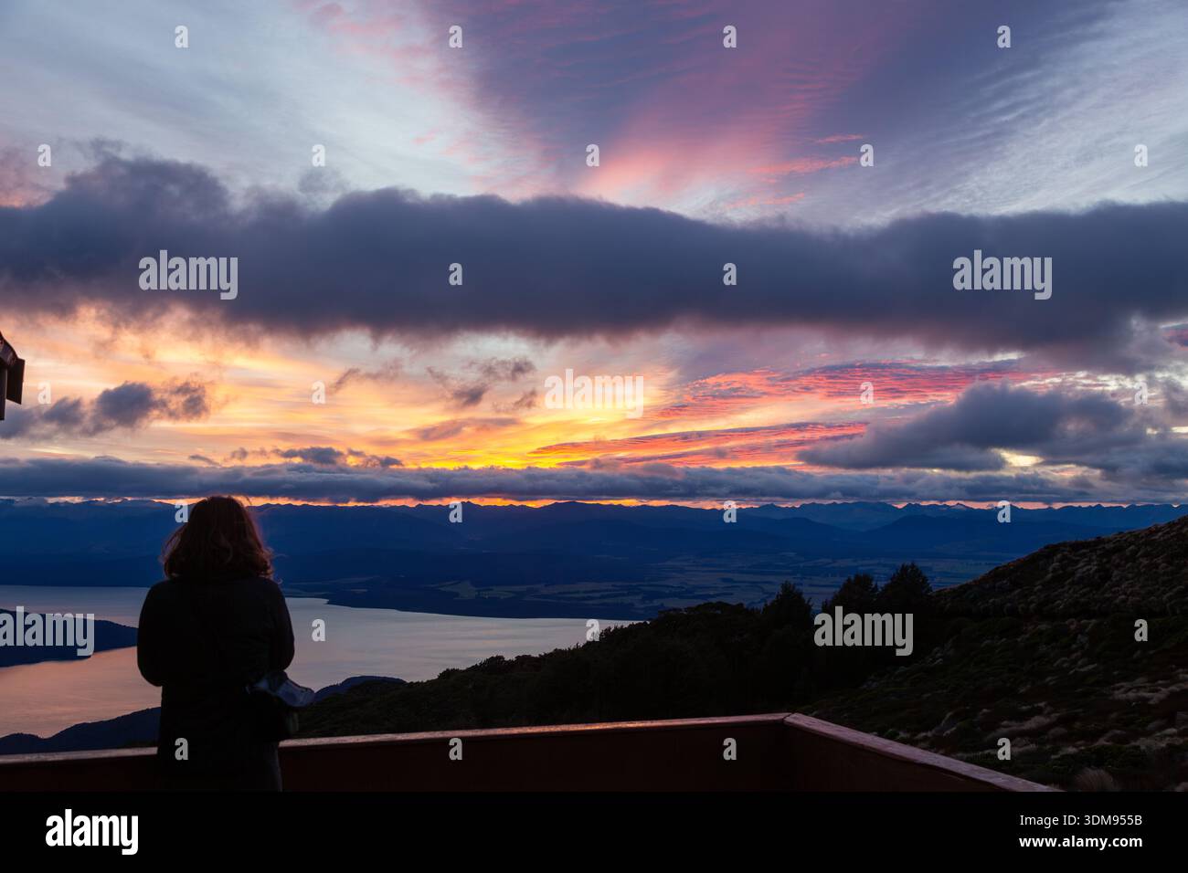 Una persona che guarda un tramonto sul Lago te Anau dalla Capanna del Monte Luxmore sul Kepler Track, te Anau, Isola del Sud, nuova Zelanda Foto Stock
