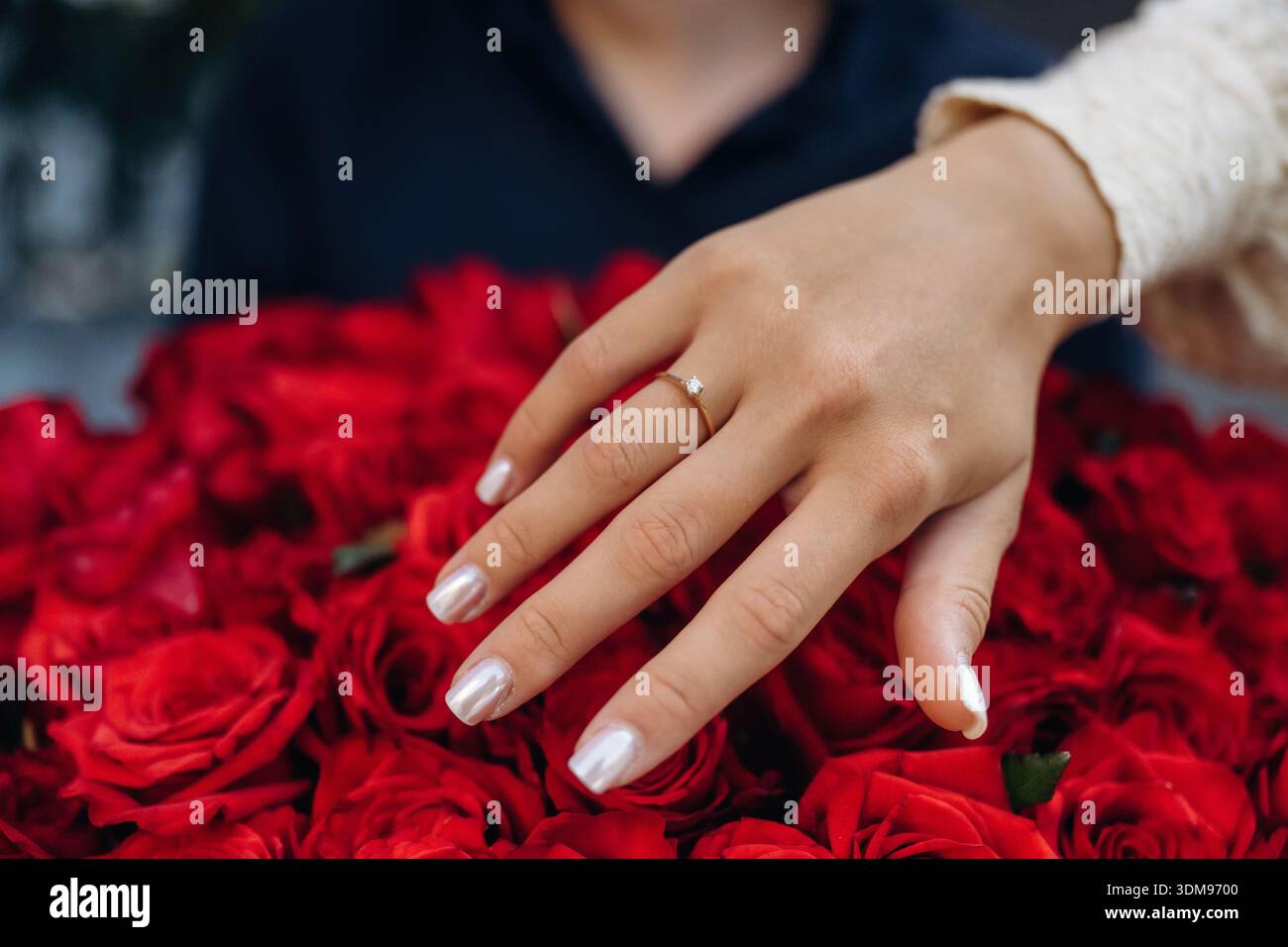 La donna ha ricevuto una proposta, mostrando un anello al dito sopra un grande mazzo di fiori rossi. Foto Stock