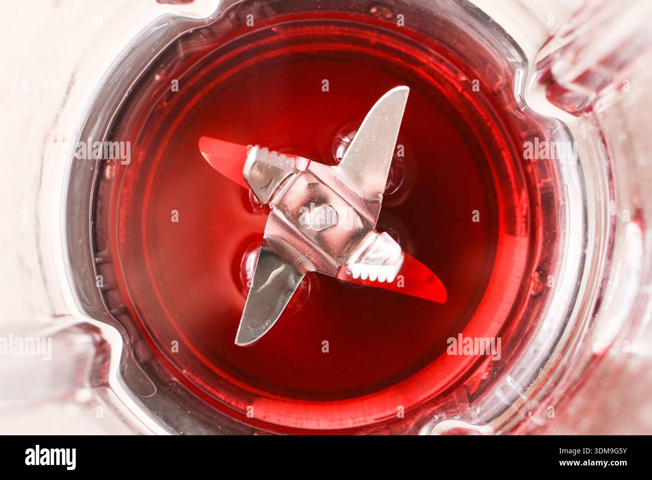 Lama del frullatore all'interno del frullato rosso. Concetto di apparecchio da cucina e preparazione degli alimenti con processo di miscelazione dei liquidi in ambienti interni. Foto Stock