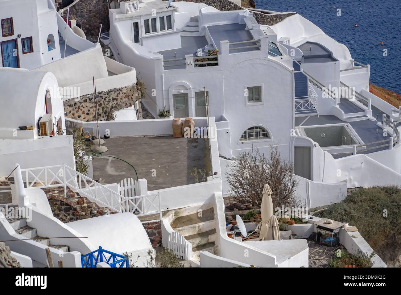 Oia (Apano Meria o Pano Meria), Santorini, Grecia. Tradizionale architettura delle Cicladi dipinta di bianco costruita nella ripida caldera sulla scogliera sopra l'AEG Foto Stock