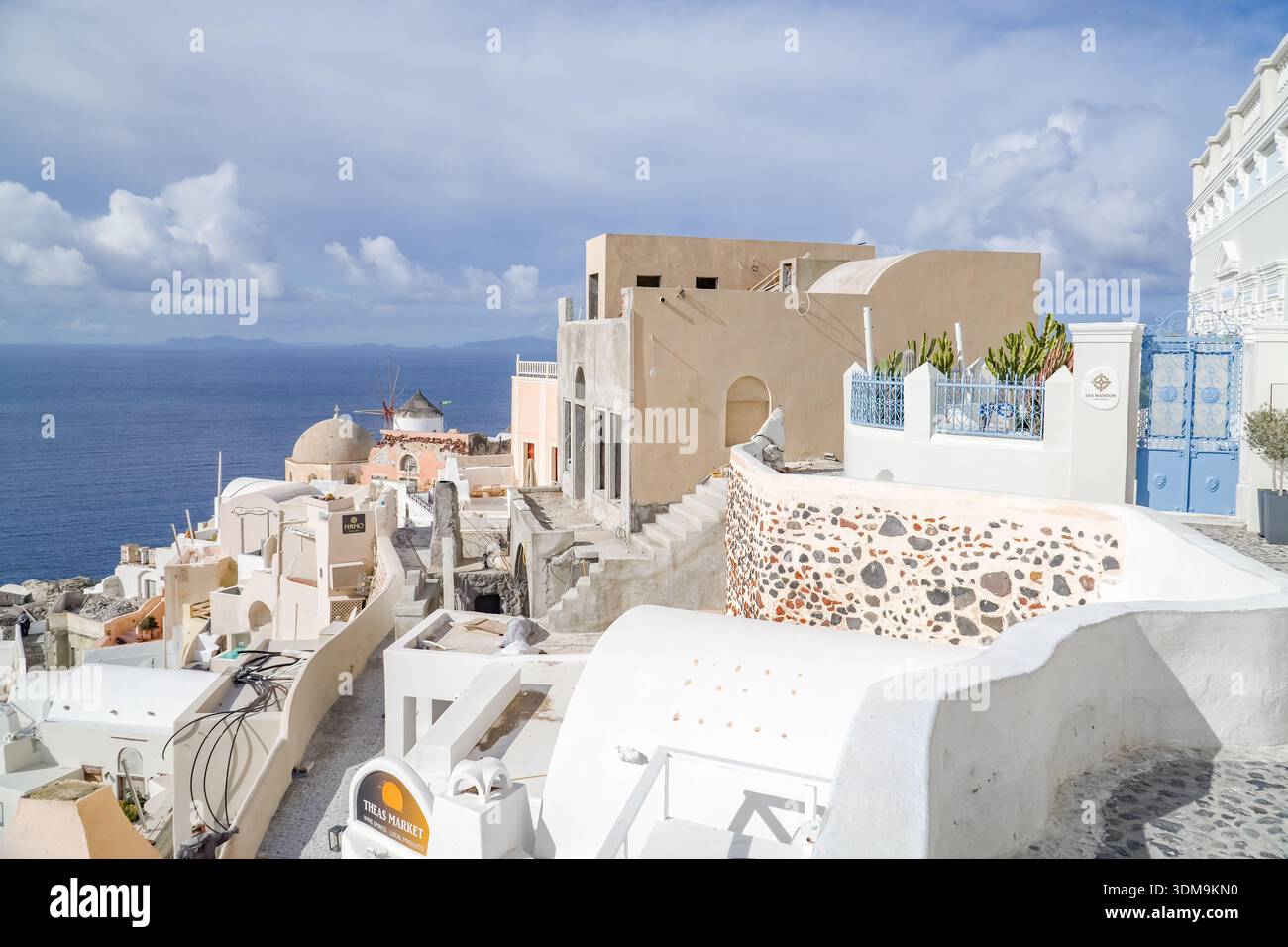 Oia (Apano Meria o Pano Meria), Santorini, Grecia. Architettura tradizionale delle Cicladi, edifici imbiancati, un mulino a vento e il blu profondo del Mar Egeo Foto Stock
