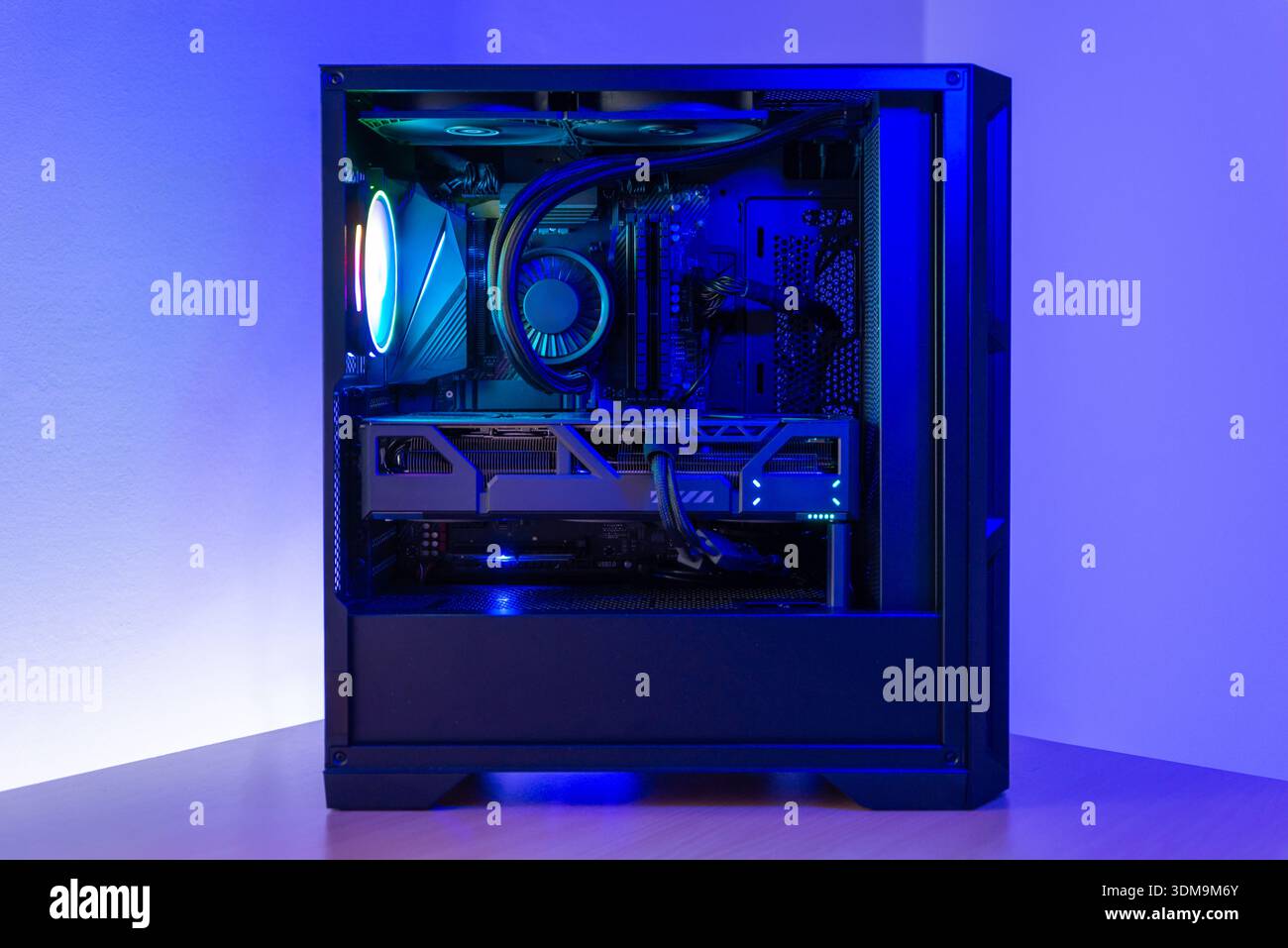 Moderno computer desktop per giochi con custodia trasparente, raffreddamento a liquido, scheda grafica e illuminazione rgb, posizionato sulla scrivania in un ambiente minimalista Foto Stock