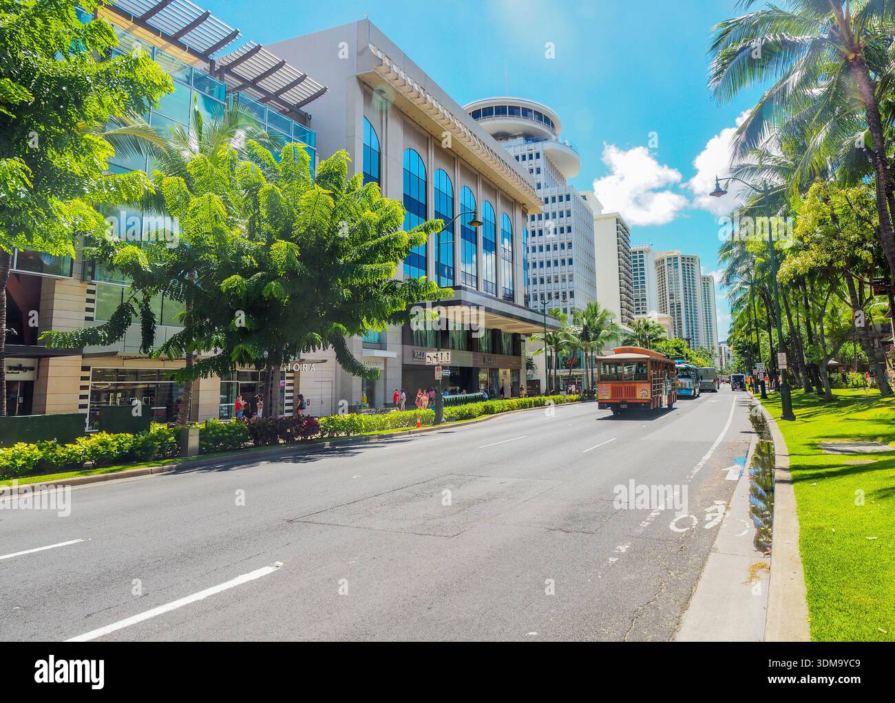 L'autobus in stile hawaiano, conosciuto come un tram, scende lungo la via principale di Kalakaua Avenue a Waikiki Foto Stock
