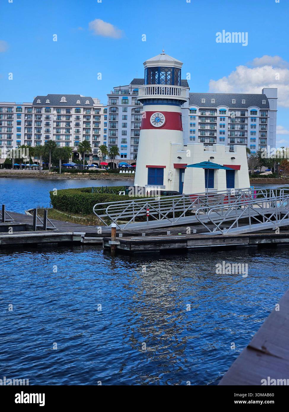 SOLO PER USO EDITORIALE. LAKE BUENA VISTA FLORIDA - 23 GENNAIO 2026: Il faro del Disney's Caribbean Beach Resort sorge sulla riva di Barefoot Bay, con l'architettura di ispirazione mediterranea del Disney's Riviera Resort sullo sfondo. - Immagine stock catturata con smartphone