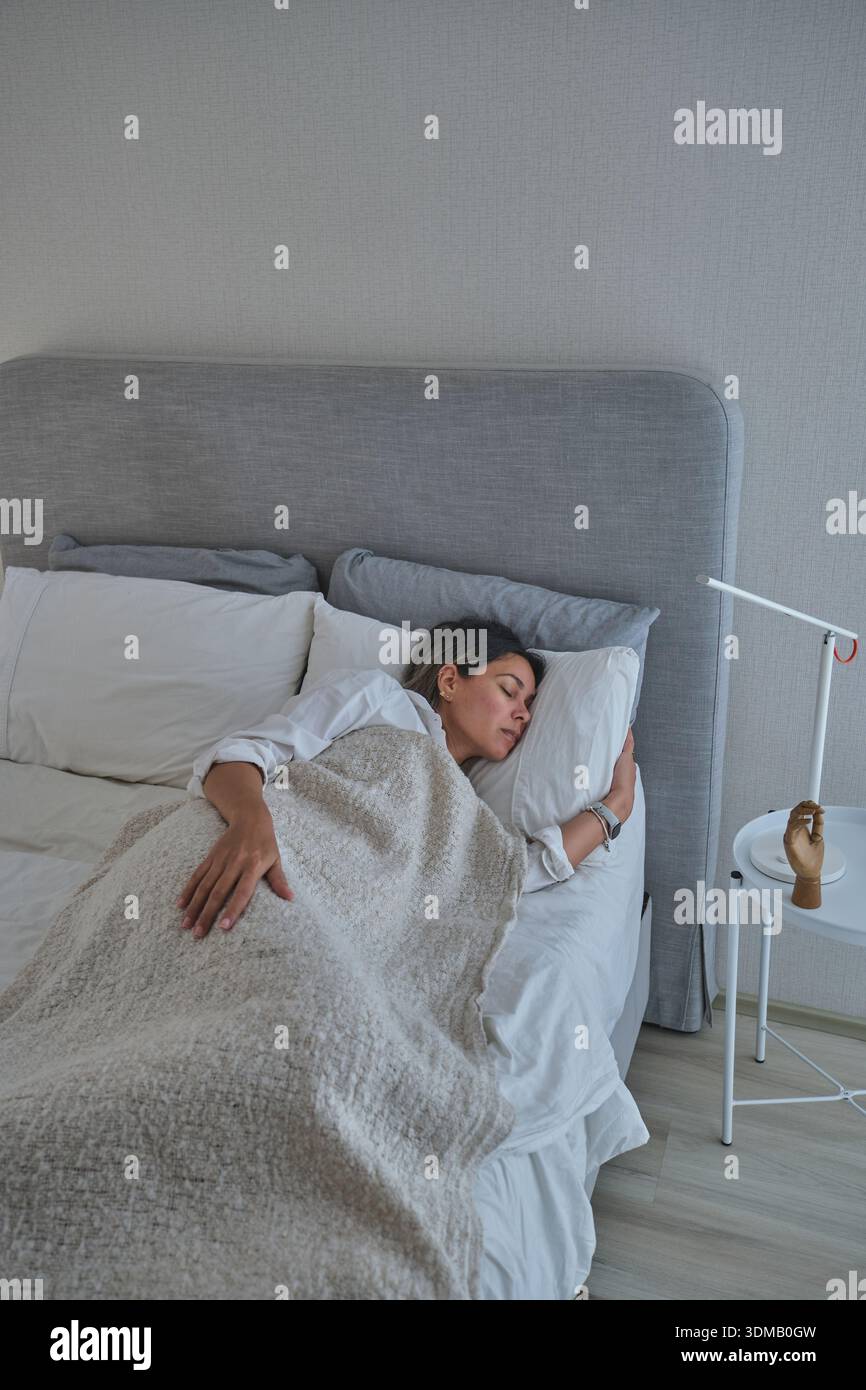 Donna che si gode un comodo riposo mattutino, abbracciando relax e benessere Foto Stock