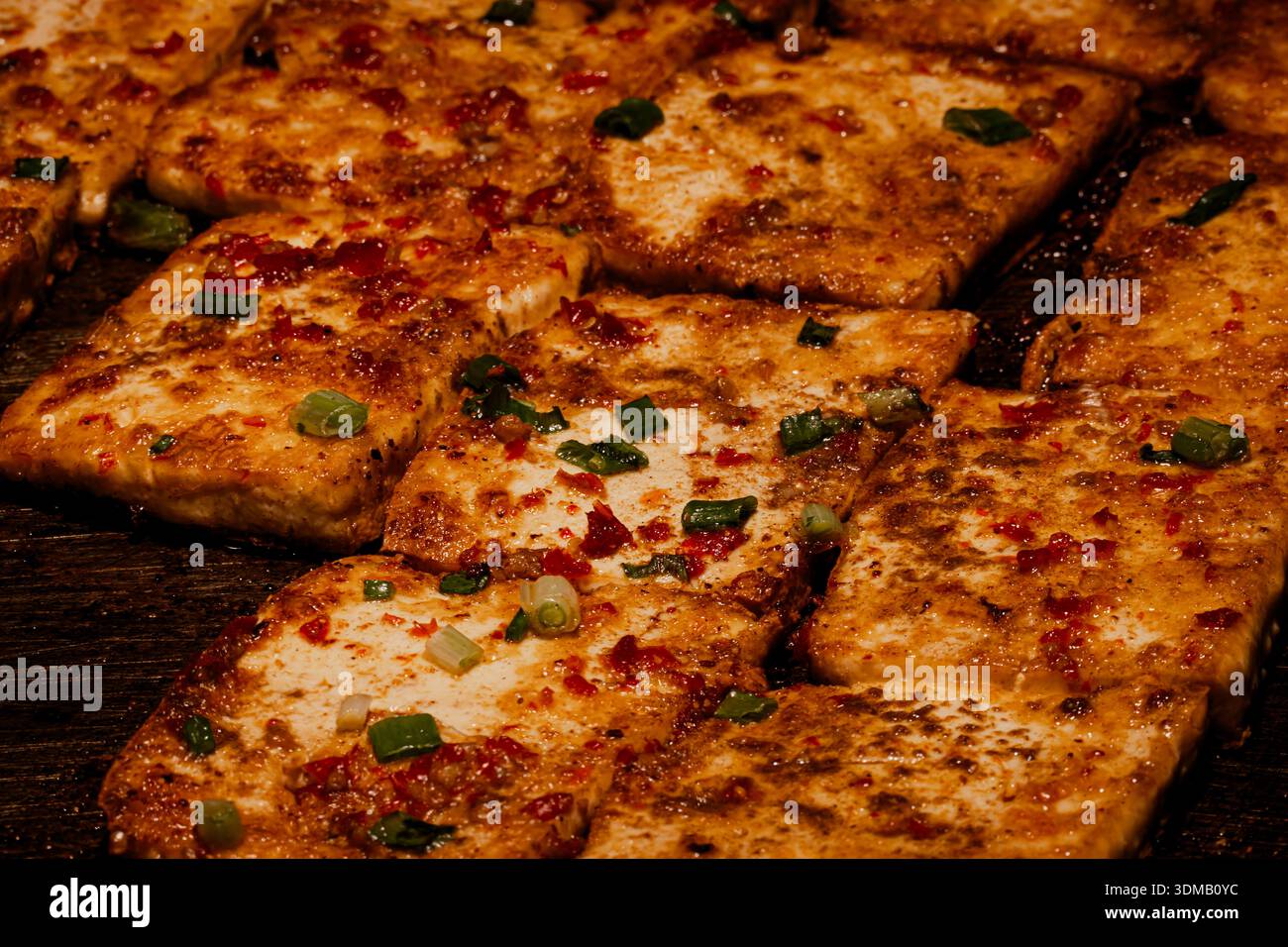 Tofu fritto sfrigolante sulla piastra di ferro Foto Stock