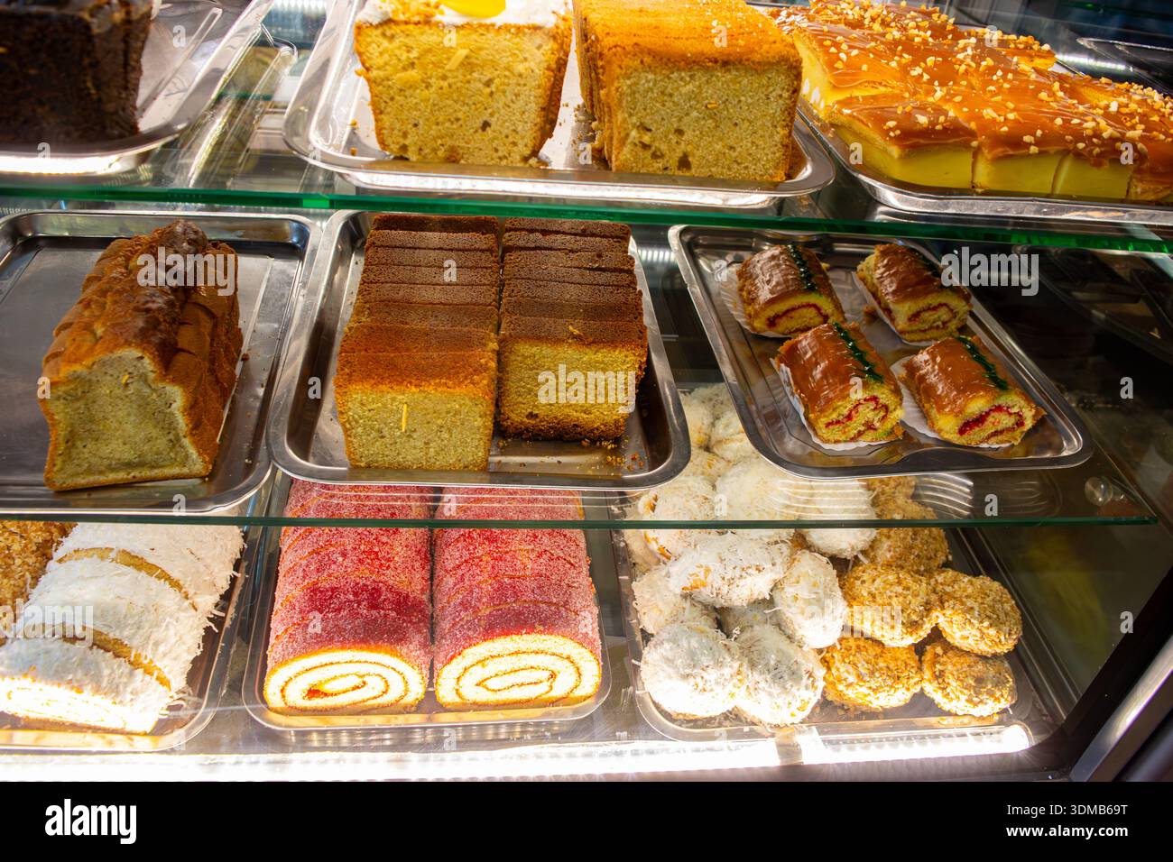 Una varieta' di torte e dolci vivaci disposti in una vetrina, che mostra diverse consistenze e colori. Foto Stock