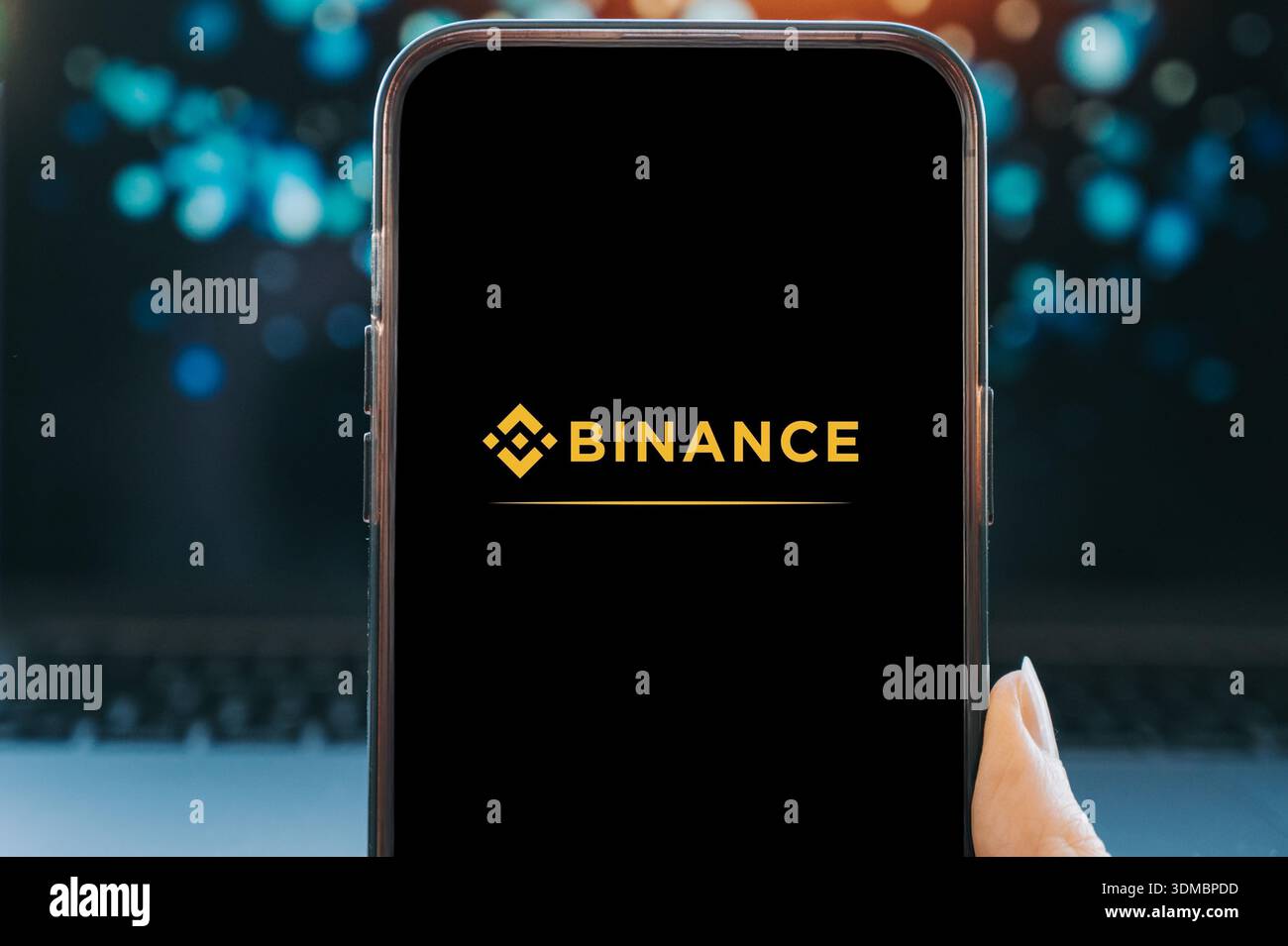 Smartphone che visualizza il logo Binance su uno schermo nero, tenuto in mano con uno sfondo sfocato. Concetto di trading di criptovalute, asset digitali, b Foto Stock