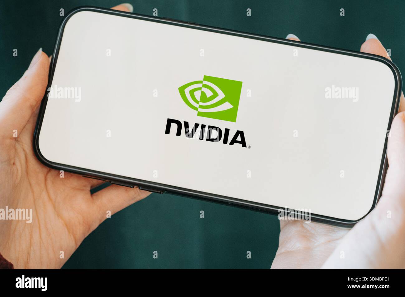 Primo piano di uno smartphone tenuto in mano che mostra il logo NVIDIA sullo schermo. Concetto di tecnologia moderna, intelligenza artificiale, GPU computing, Foto Stock