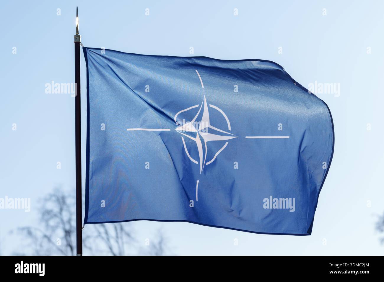 La bandiera della NATO sventolava nel vento contro un cielo azzurro. Foto Stock