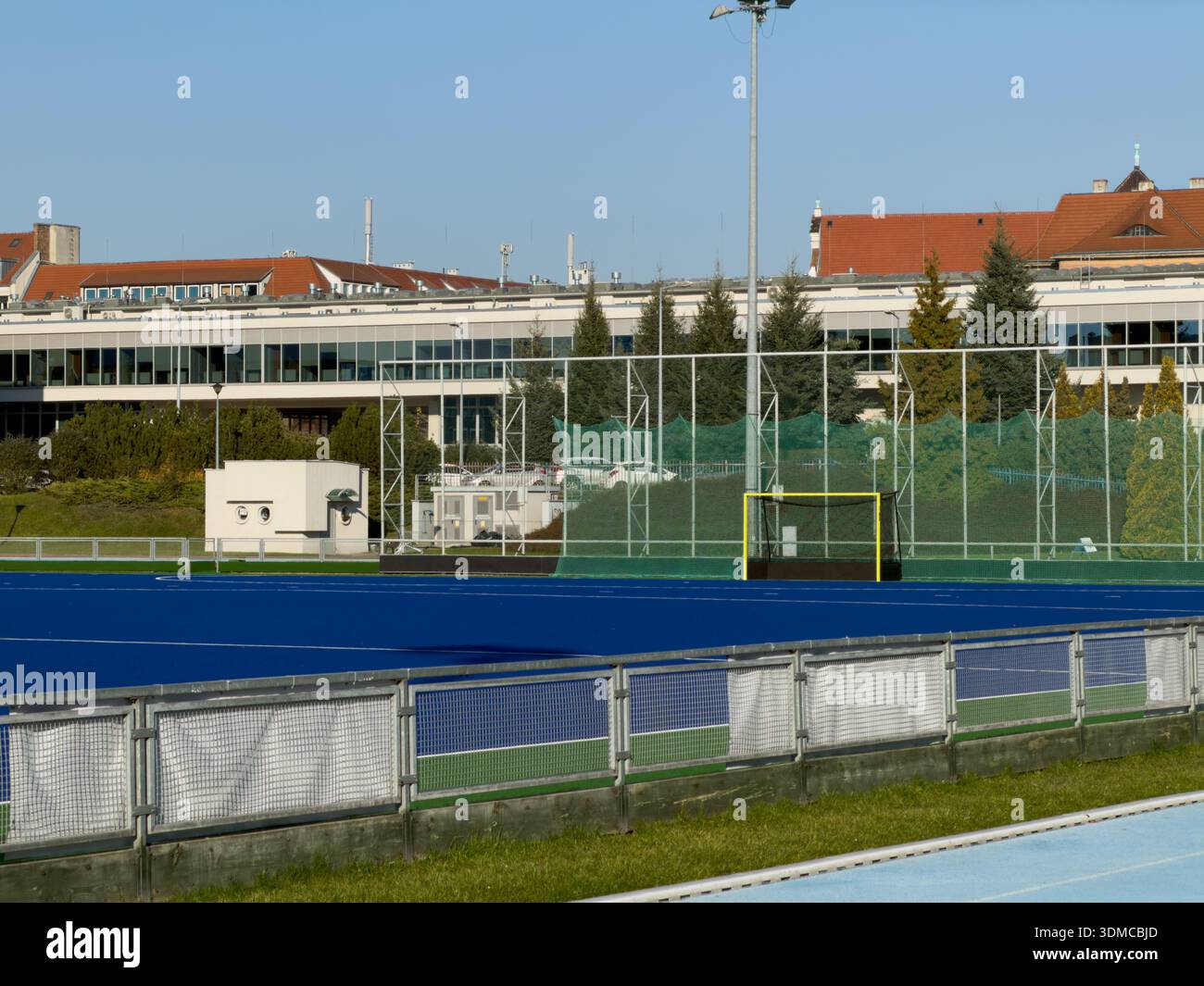 Poznan, Polonia - 18 novembre 2025: Un chiaro complesso sportivo all'aperto con un campo da hockey su prato blu, un gol giallo e una rete di sicurezza, perf Foto Stock