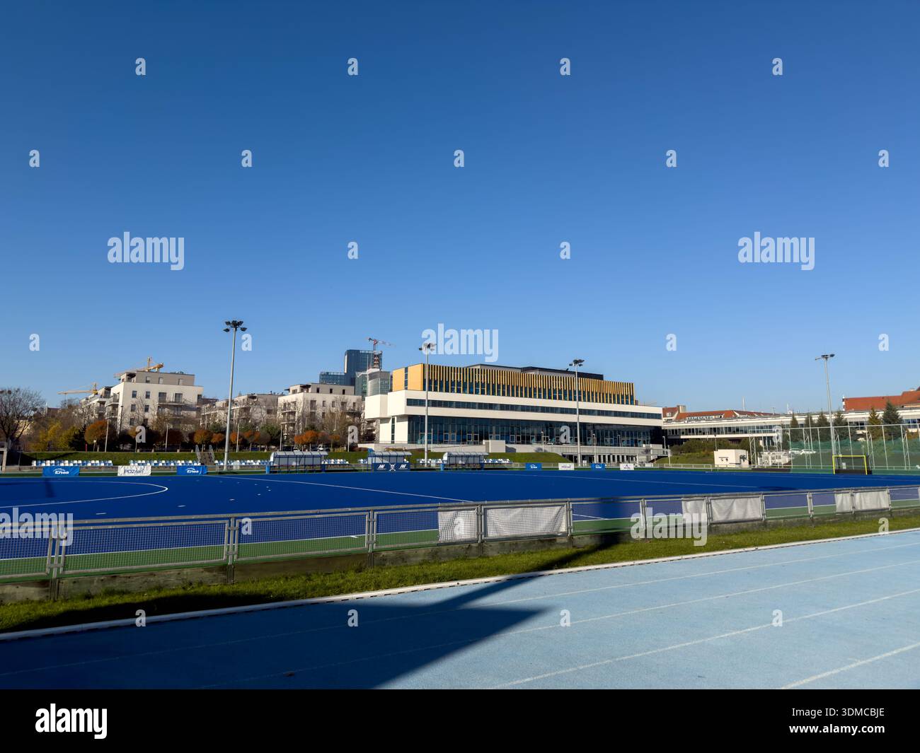 Poznan, Polonia - 18 novembre 2025: Vivace campo da hockey su prato blu e pista da corsa, con marchio PZU Sport, situato in un moderno complesso sportivo Foto Stock