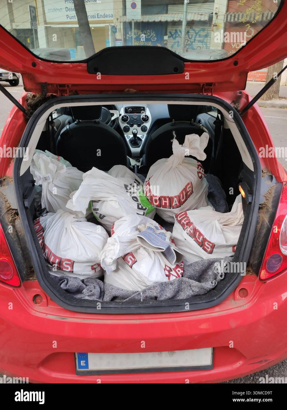 Dettaglio del bagagliaio di una piccola utilitaria Ford Ka riempita di sacchi di rune per i lavori sul pavimento Foto Stock