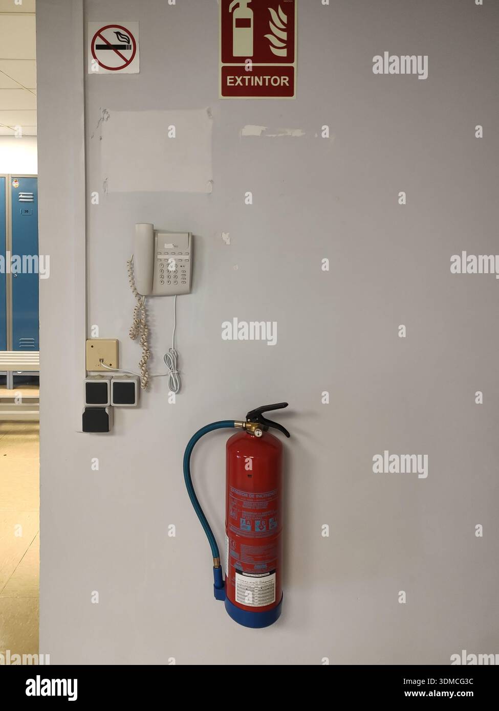 Fotografia verticale dello spogliatoio di un dipendente dell'azienda. Sulla parete è appeso un estintore, un telefono interno, prese di corrente, un commutatore Foto Stock