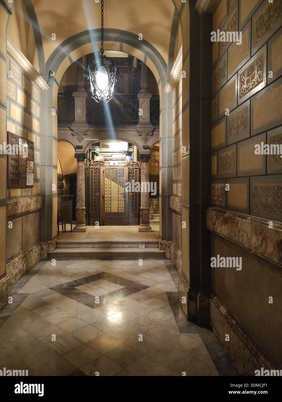 Fotografia verticale di un'antica e bellissima entrata di un edificio residenziale di Barcellona. Pavimento e decorazioni in marmo, soffitto alto e una i battuto Foto Stock