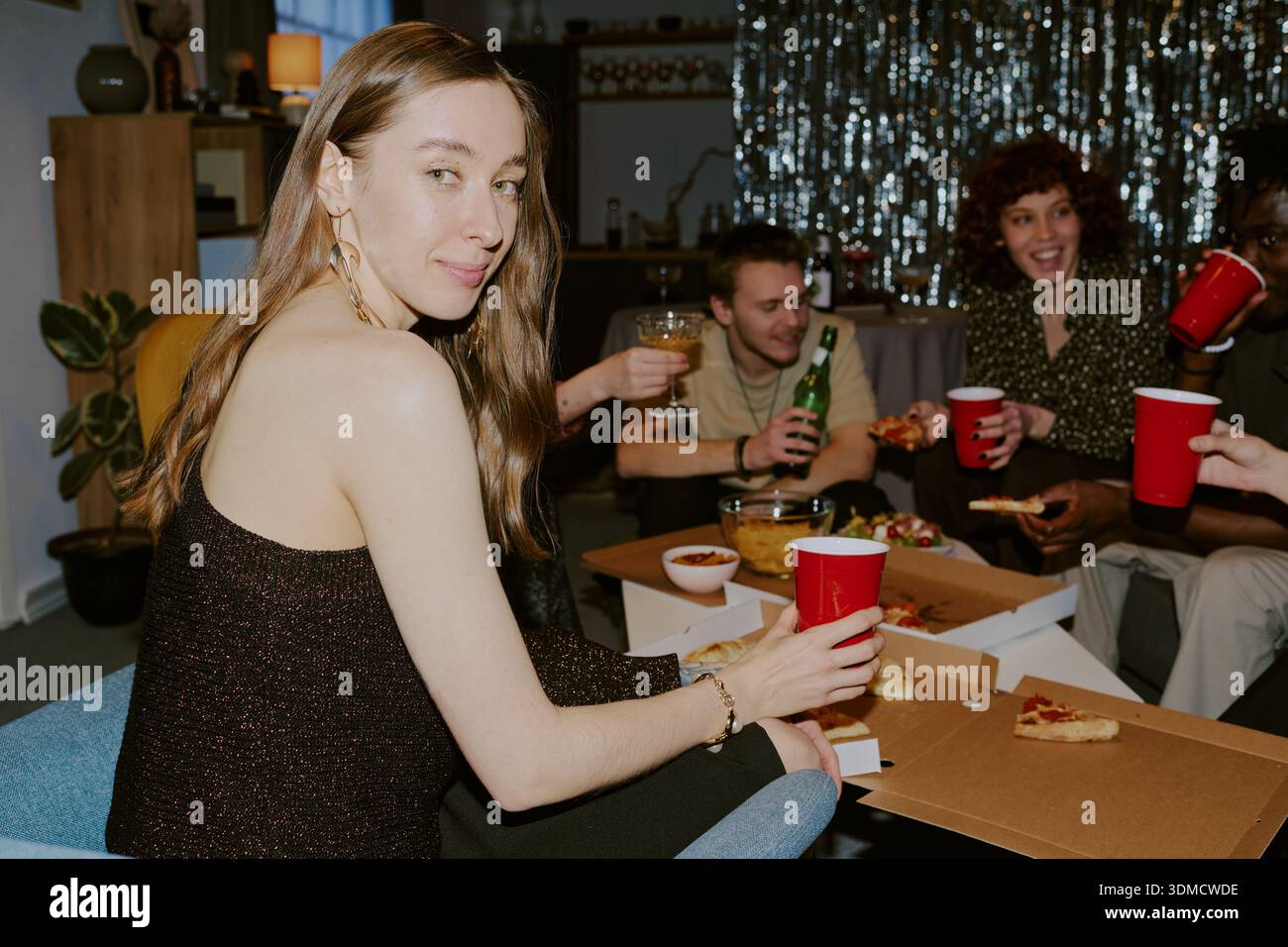 Ritratto di una giovane donna caucasica che sorride mentre festeggia con gli amici Foto Stock
